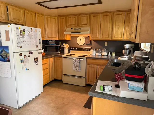 Kitchen featuring light wood cabinetry, dark countertops, and resilient flooring