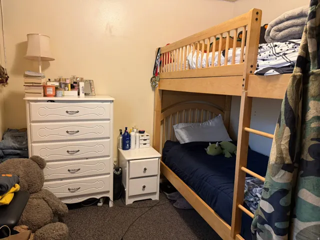 Natural wood-finish bunk bed with a built-in ladder, complemented by a white five-drawer dresser and a matching two-drawer nightstand