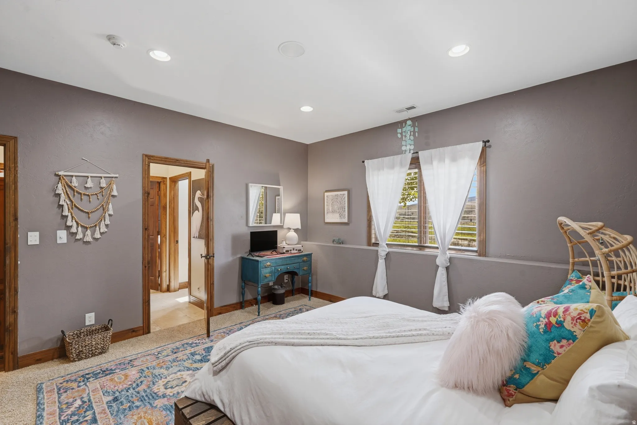 Carpeted room featuring a window with natural wood trim and white curtains