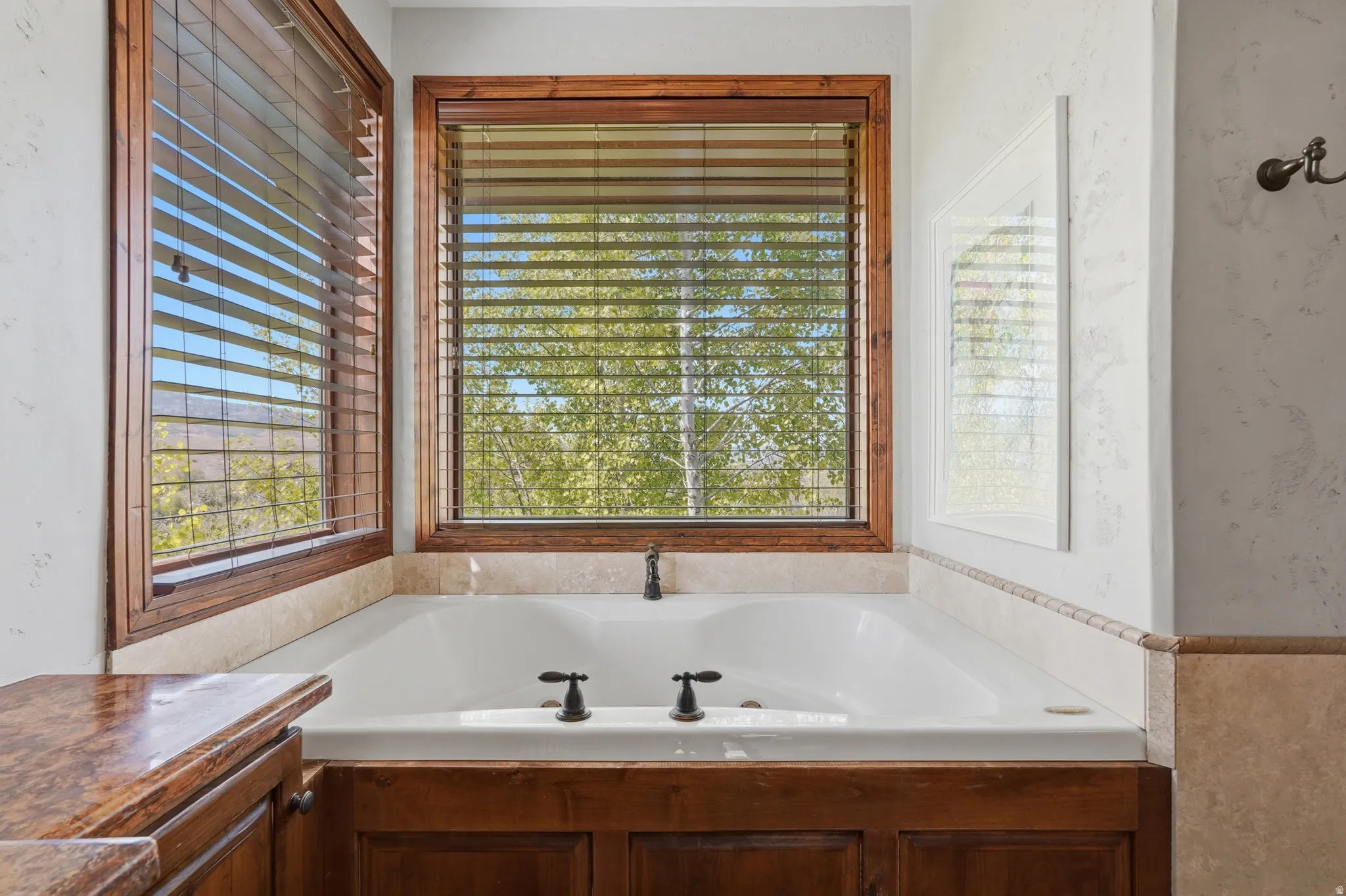 Corner soaking tub with bronze fixtures set into a wood-finish surround