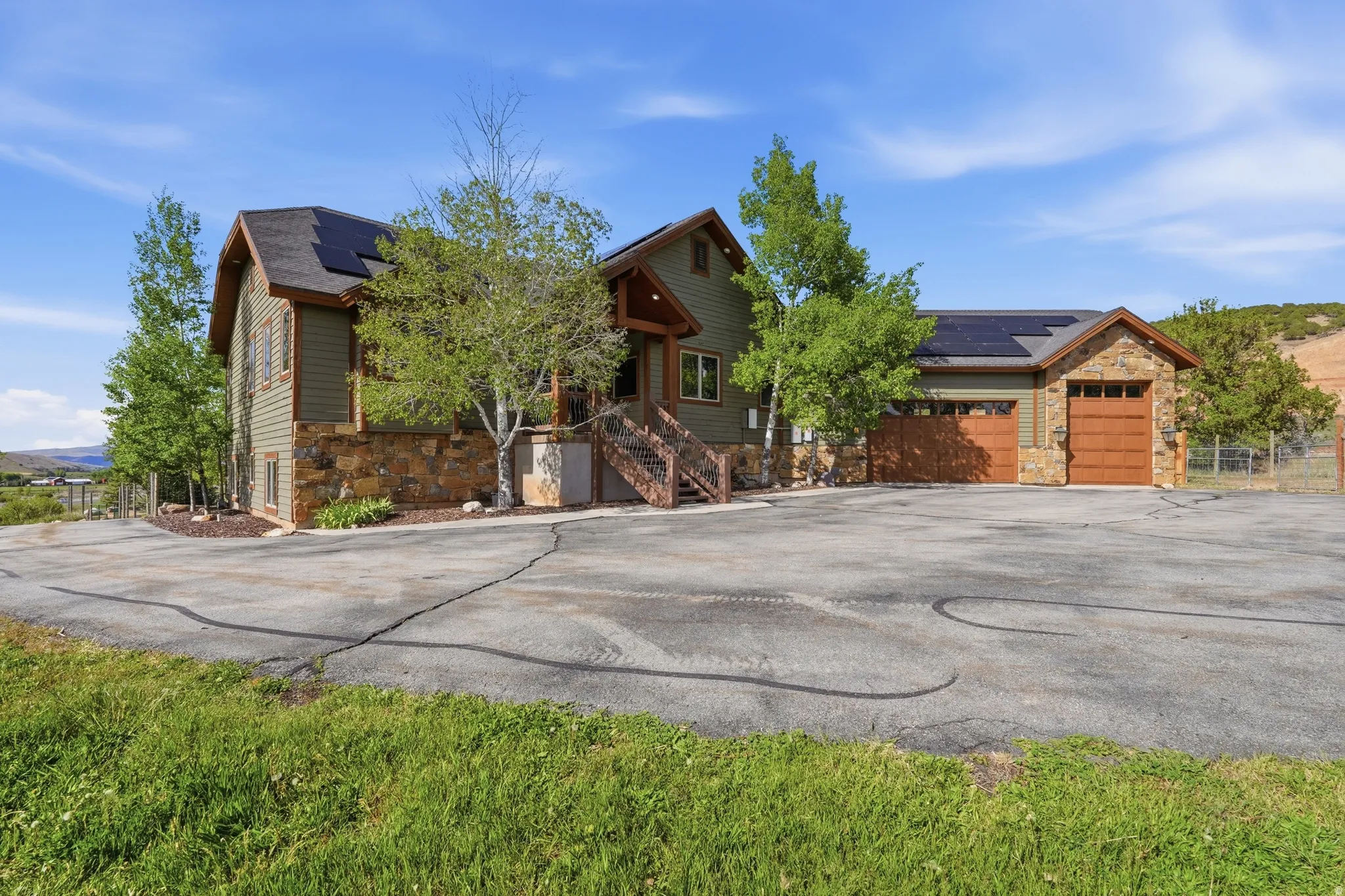 Craftsman-style exterior featuring a stone and siding facade, natural wood garage doors, and a multi-pitch roof