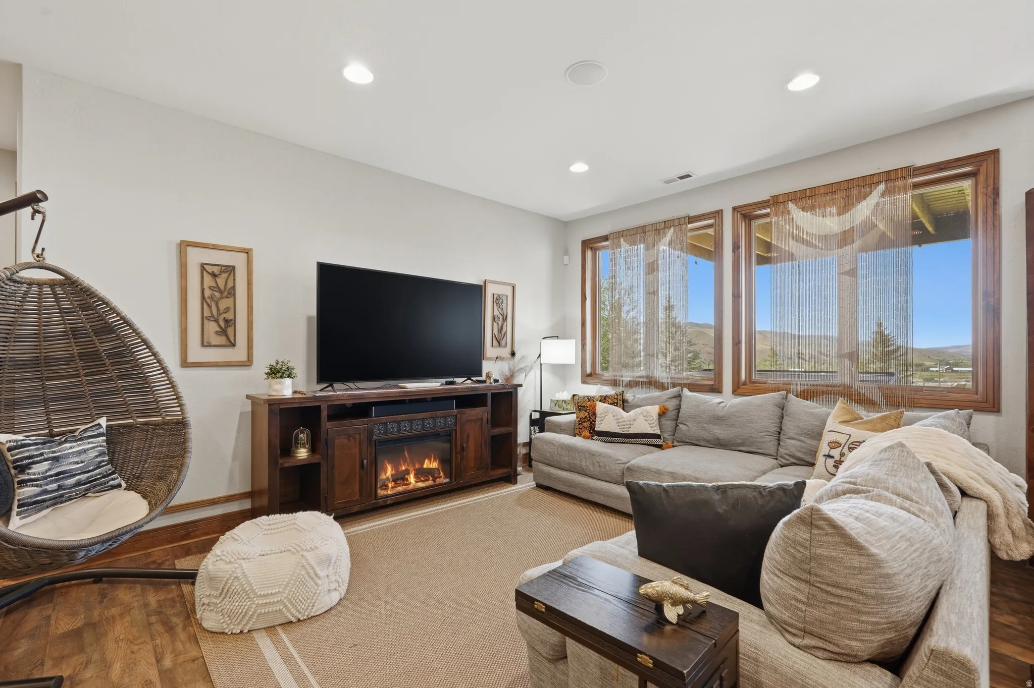 Bright living space featuring recessed lighting, wood-finish flooring, and large windows with natural wood trim