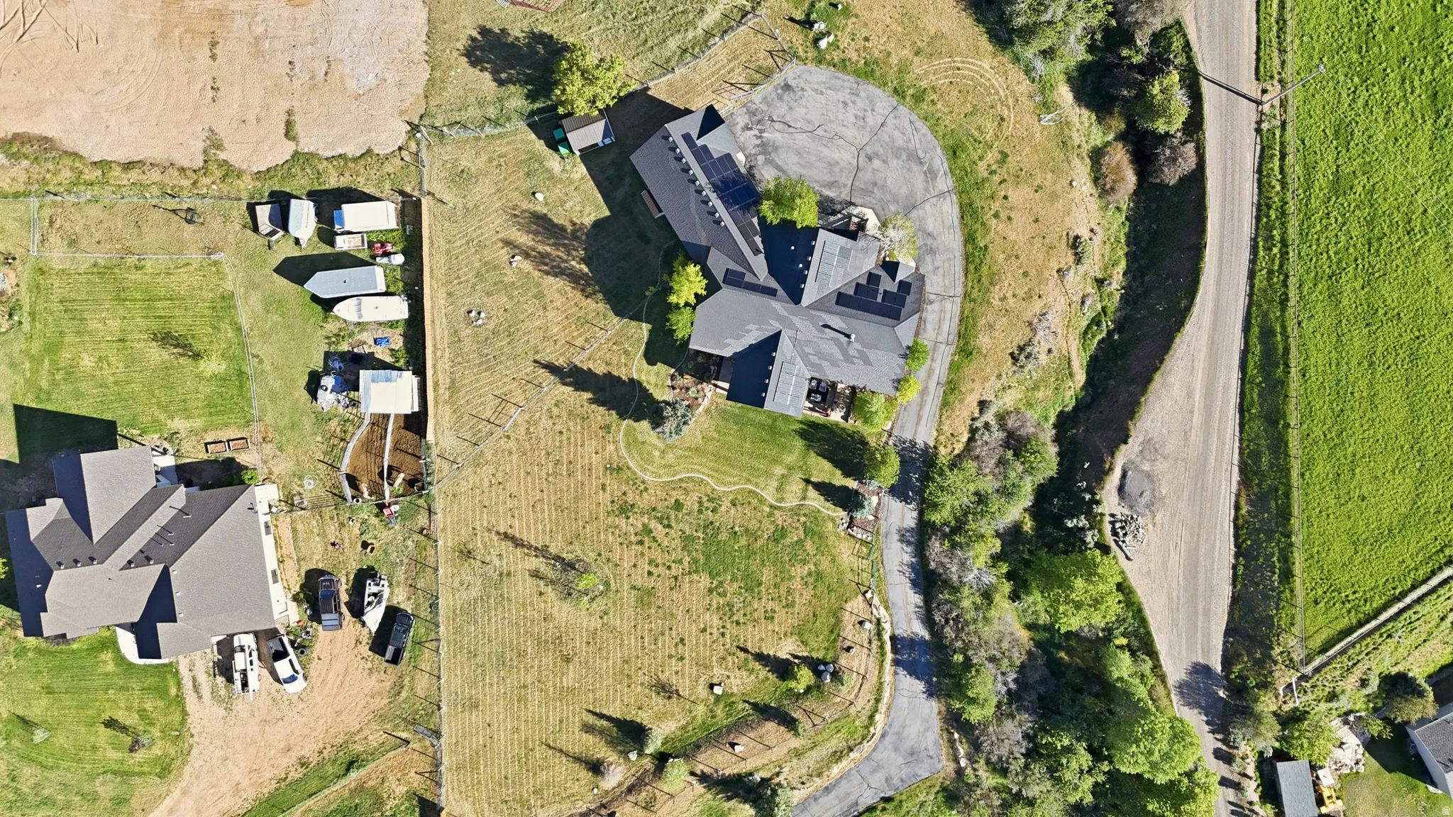 Expansive property featuring two distinct structures with dark roofs and light-colored siding