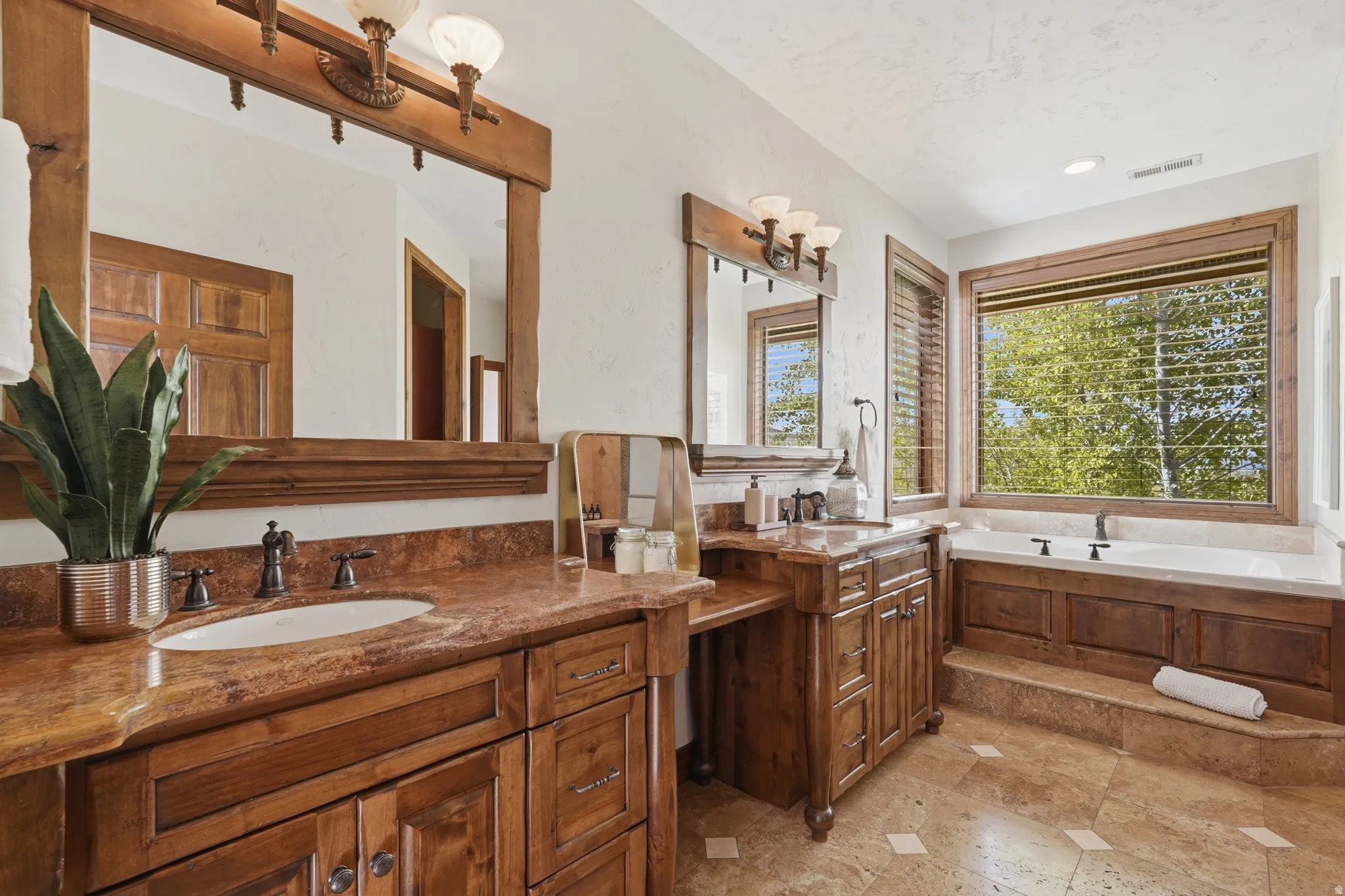 Spacious bathroom featuring dual wood vanities with undermount sinks and stone countertops