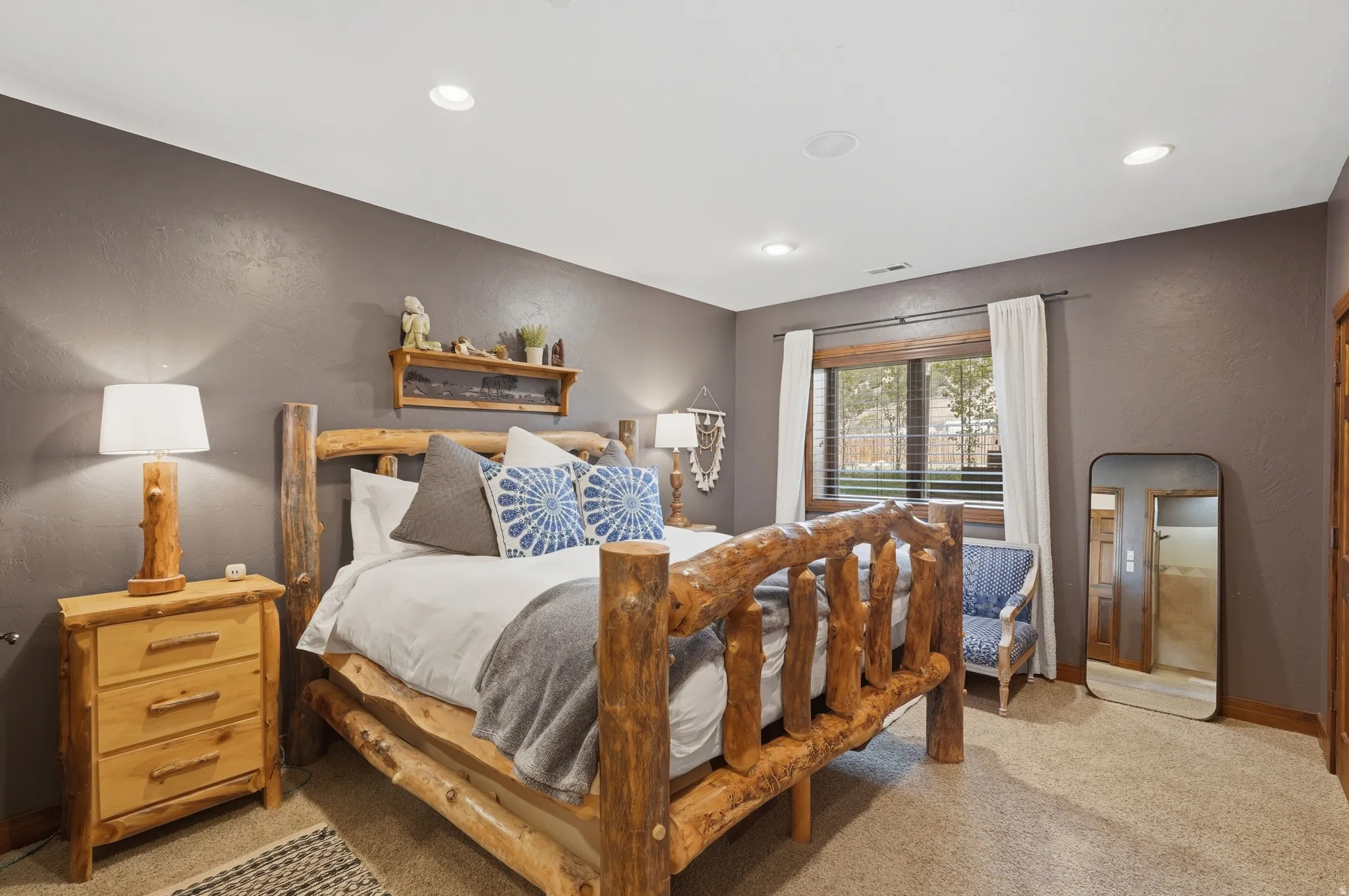 Spacious room featuring textured gray walls, recessed lighting, and a large window with white curtains
