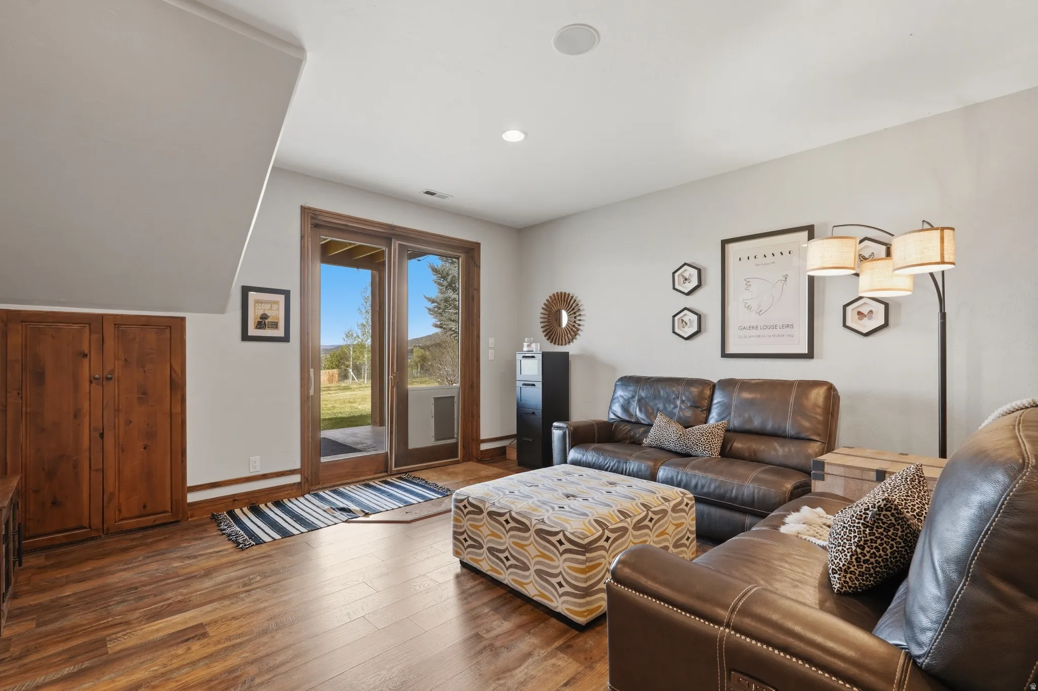 Spacious living area featuring wood-finish flooring, light grey wall paint, and a built-in wooden cabinet
