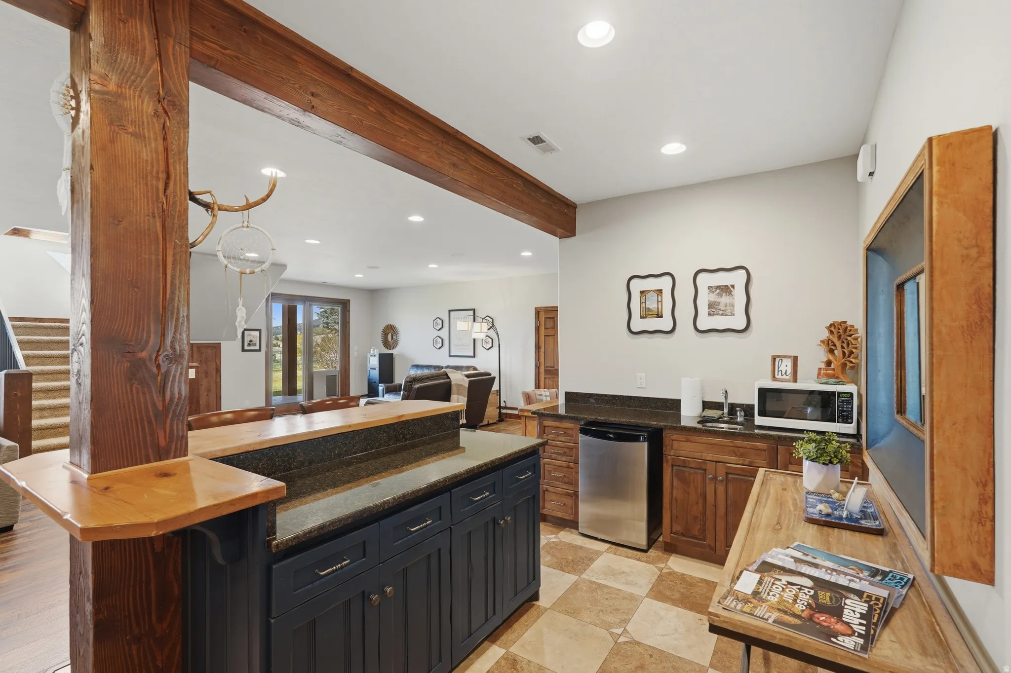 Open-concept recreational space featuring a wet bar with a stainless steel mini-fridge, built-in cabinetry, and tile flooring