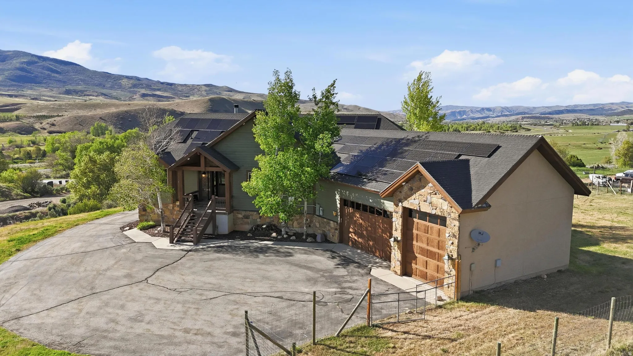 Multi-level residence featuring a dark green exterior, stone accents, and a prominent front entry with wooden steps