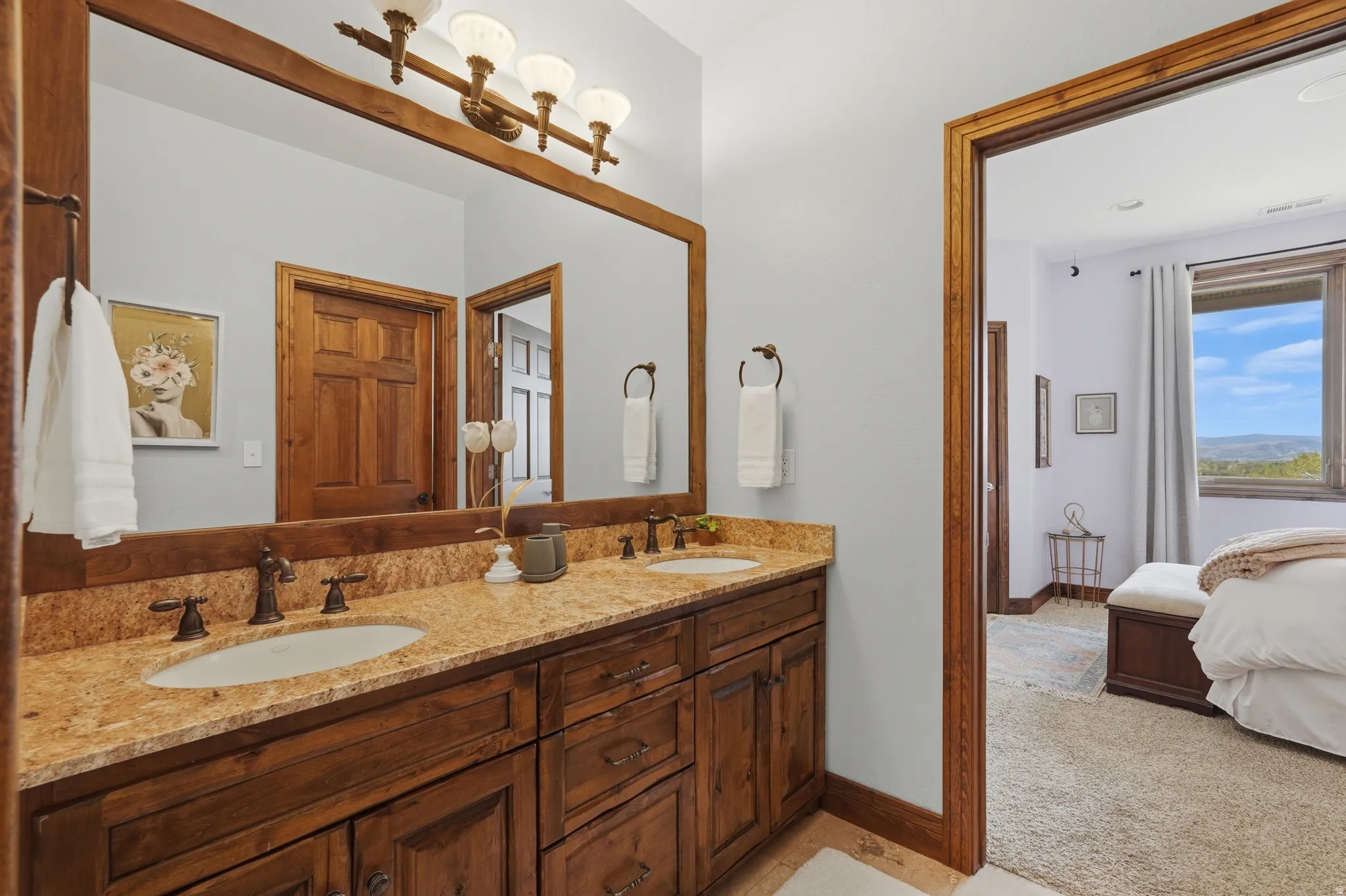Double vanity with a granite countertop, dual undermount sinks, and dark bronze hardware