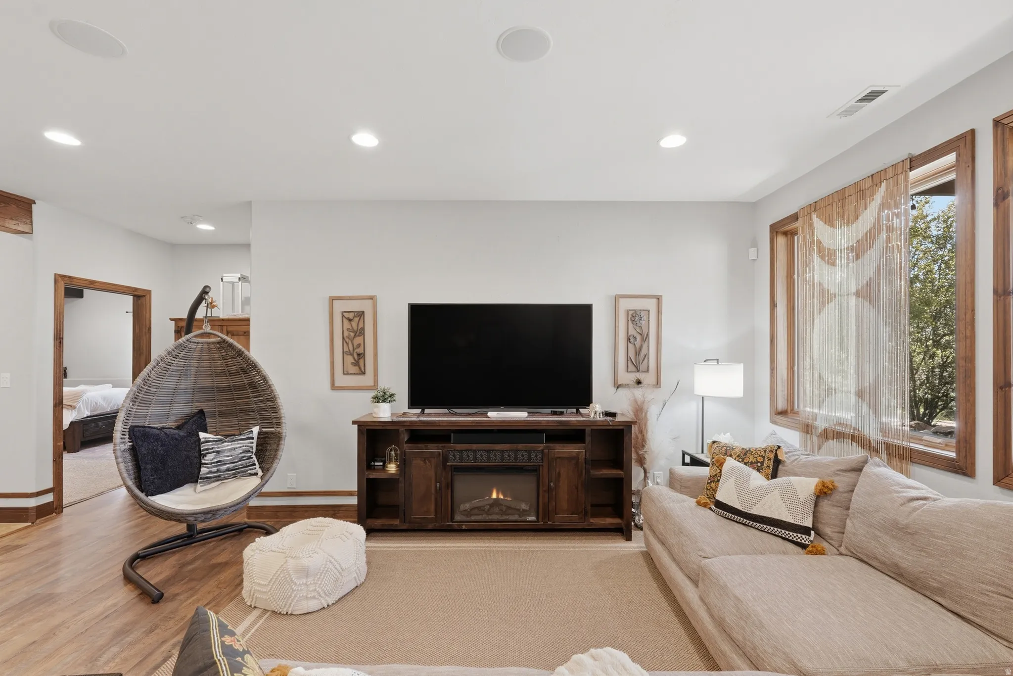 Entertainment space featuring a built-in media console with an electric fireplace, recessed lighting, wood-finish flooring, and natural wood window trim