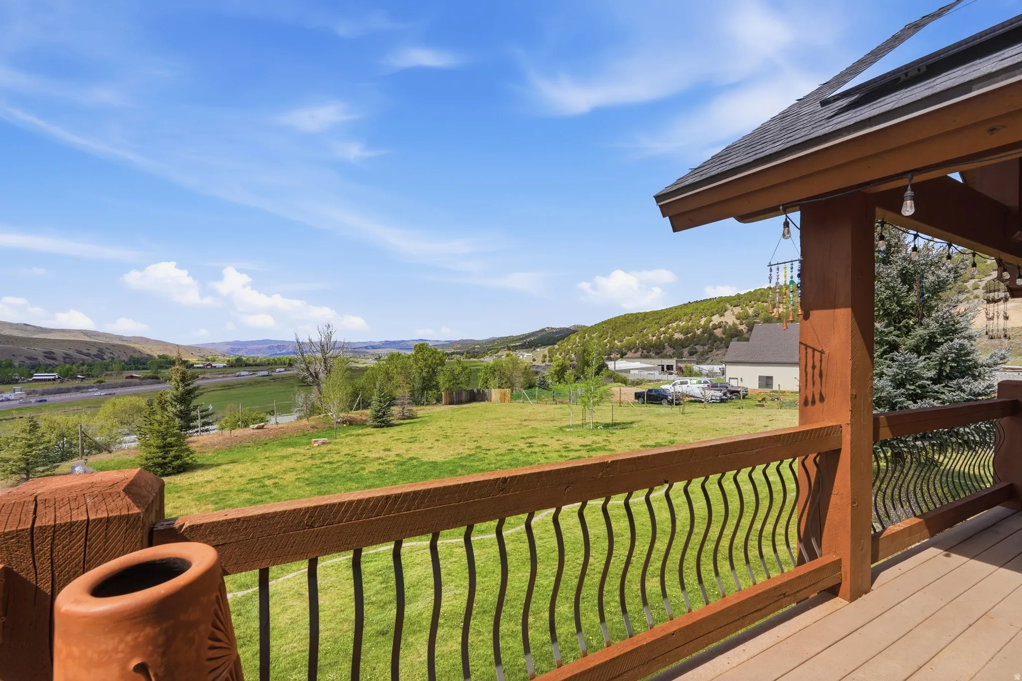 Expansive outdoor deck featuring wood-finish flooring, a sturdy wood railing with decorative metal balusters, and an overhead roof structure
