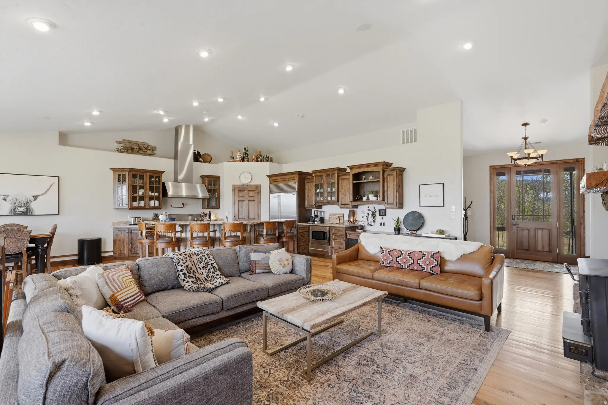 Open-concept living space featuring wood-finish flooring, recessed lighting, and a vaulted ceiling