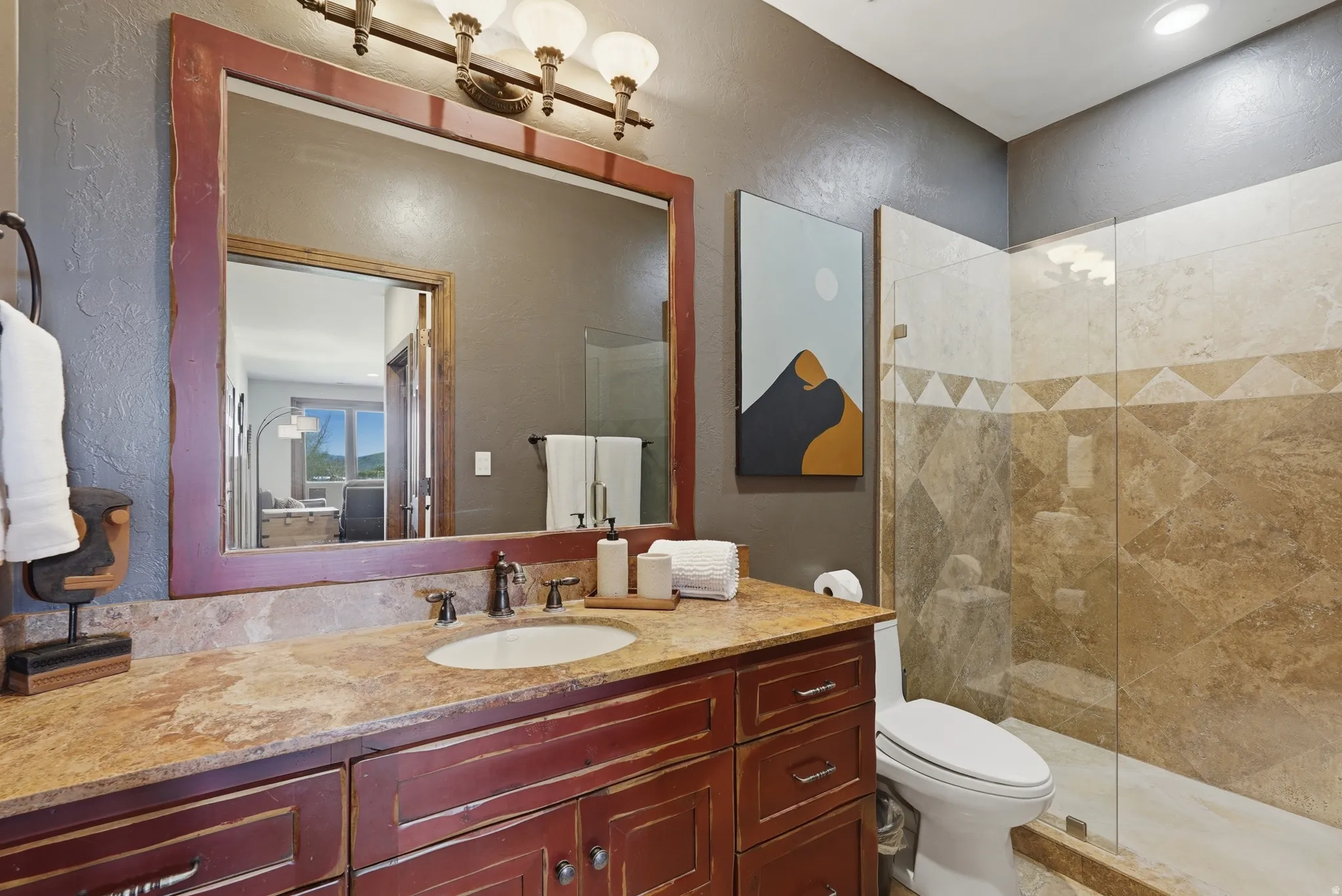Vanity with a stone countertop, an integrated sink, and a dark wood-finish base