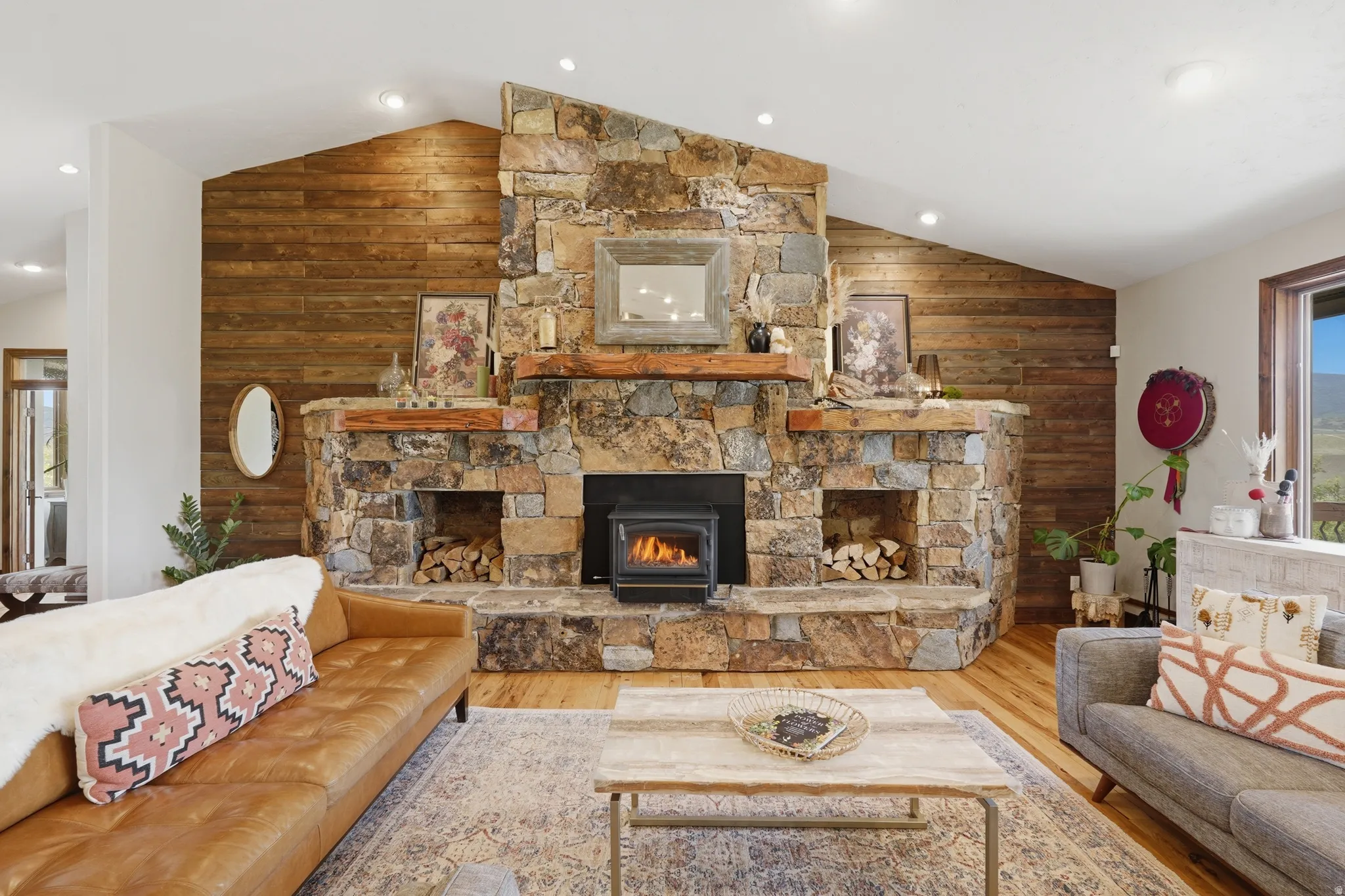 Stone fireplace with wood-burning stove, flanked by built-in wood storage niches