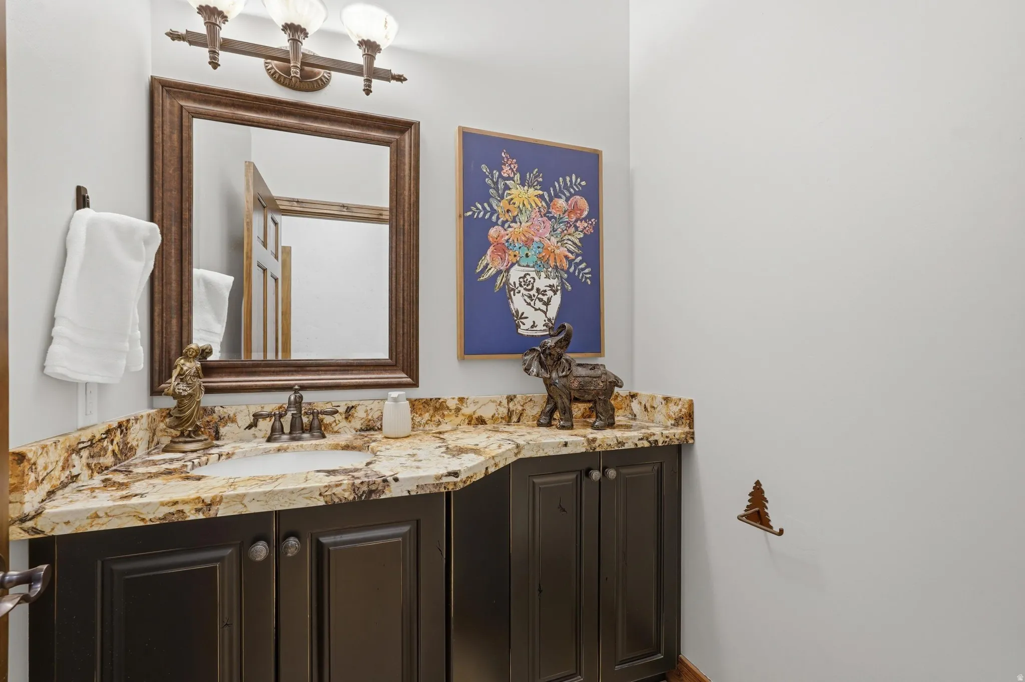 Bathroom vanity featuring a vessel sink, rich brown cabinetry, and a patterned stone countertop