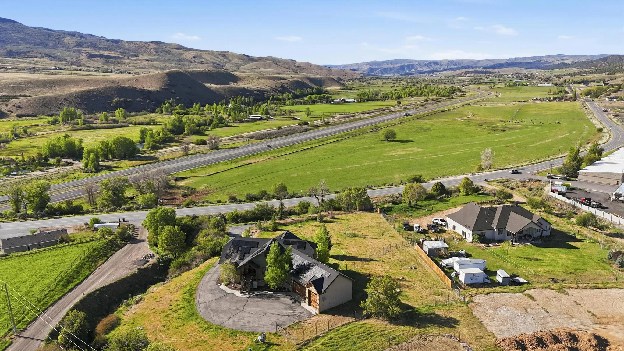 Aerial perspective showcasing a sprawling landscape with agricultural fields, distant mountains, and a curving roadway