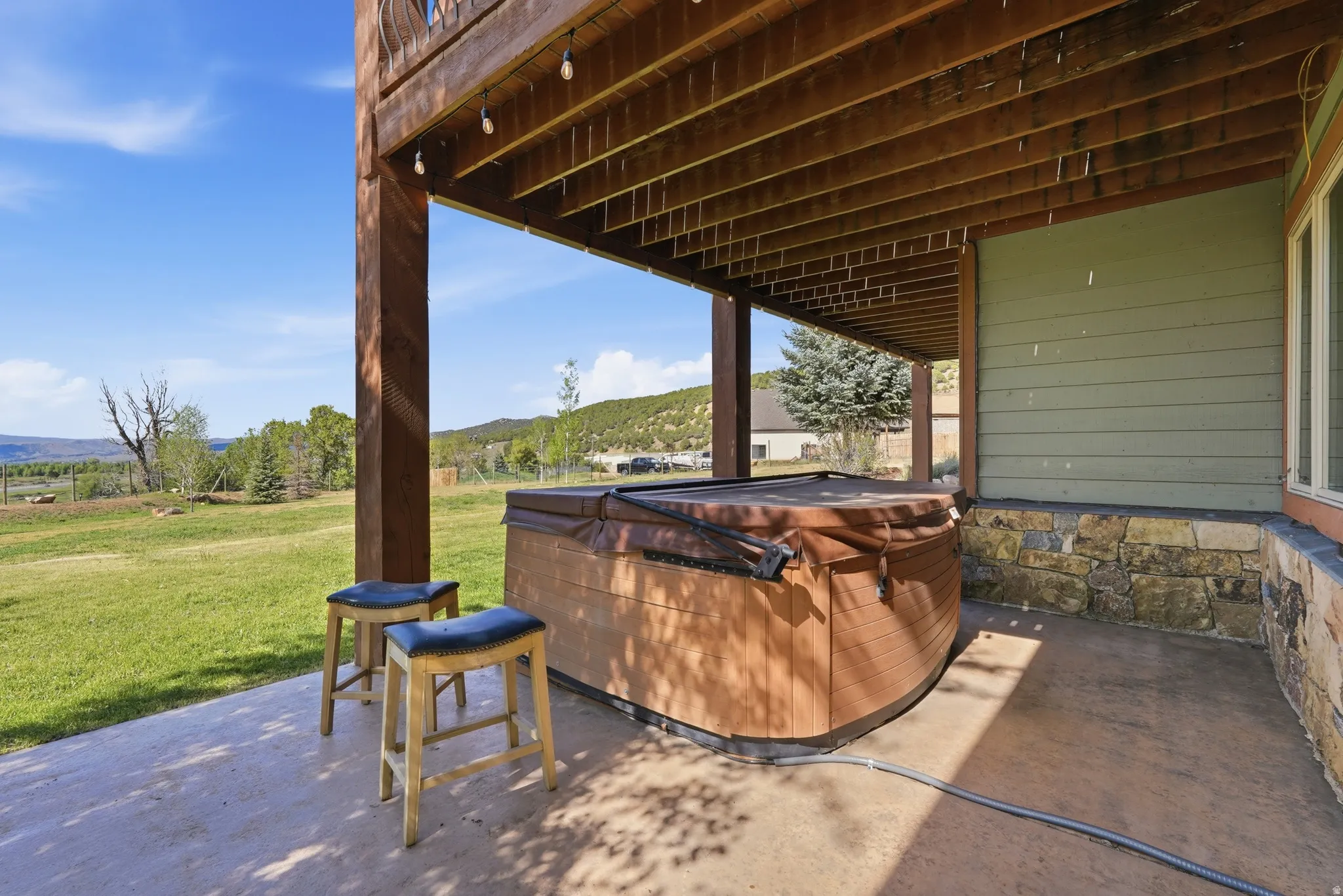 Outdoor patio featuring a covered spa, wood-plank soffit, and exposed wood beam supports