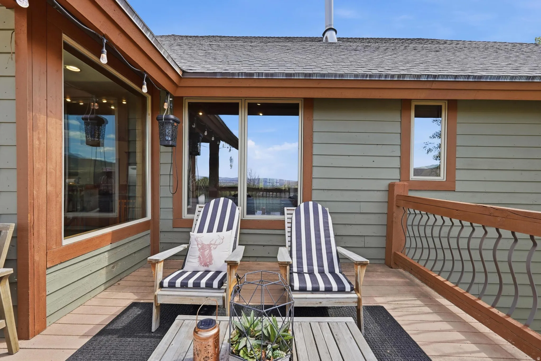 Expansive deck featuring wood-finish flooring, a decorative metal railing, and string lighting