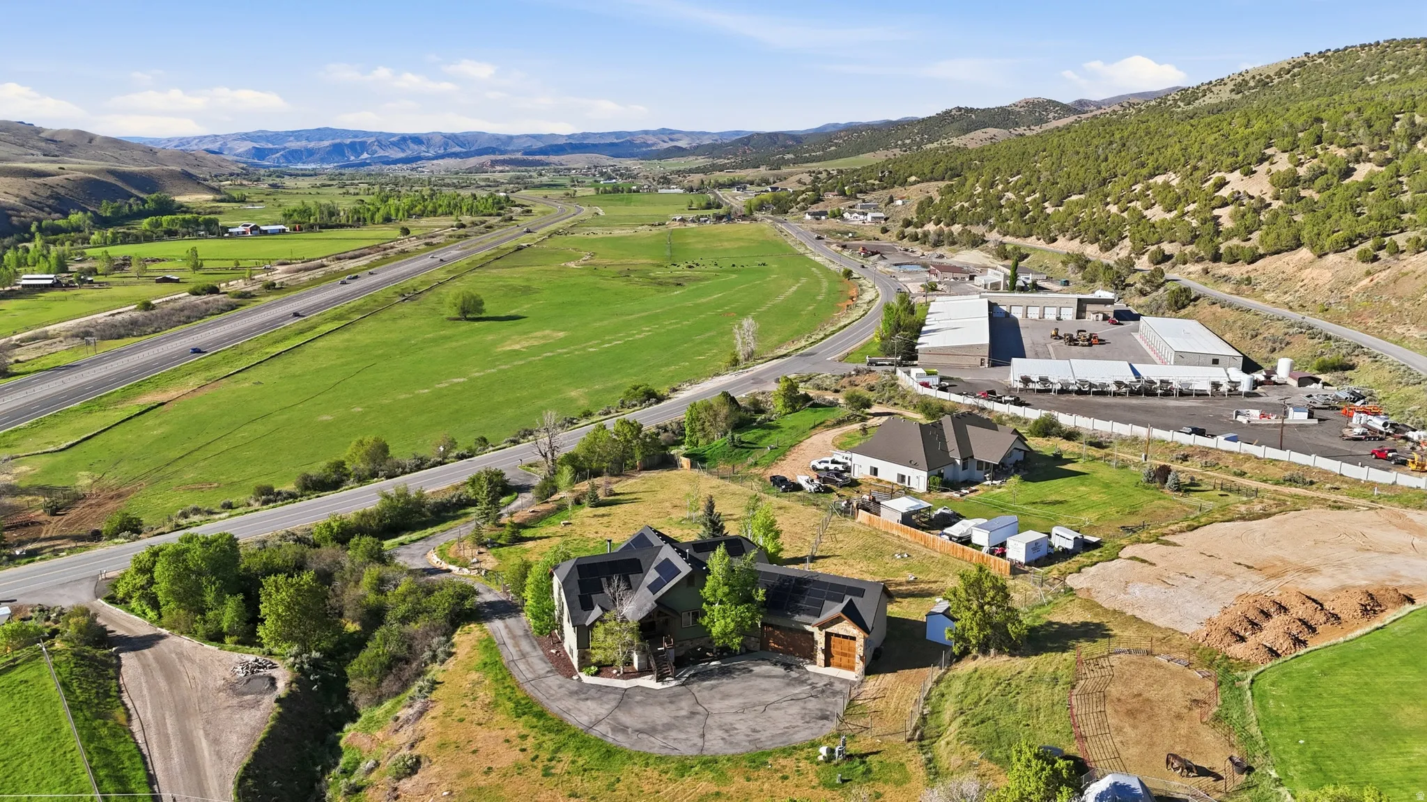 Spacious property featuring two residential structures and expansive green fields, bordered by a multi-lane roadway