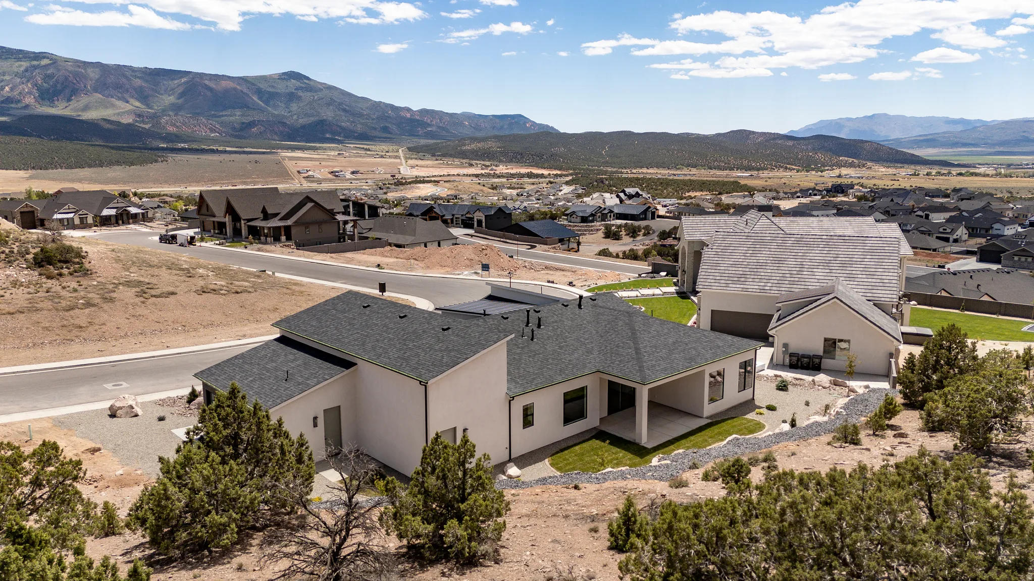 Contemporary residence featuring a covered patio, landscaped terraced yard, and a two-car garage