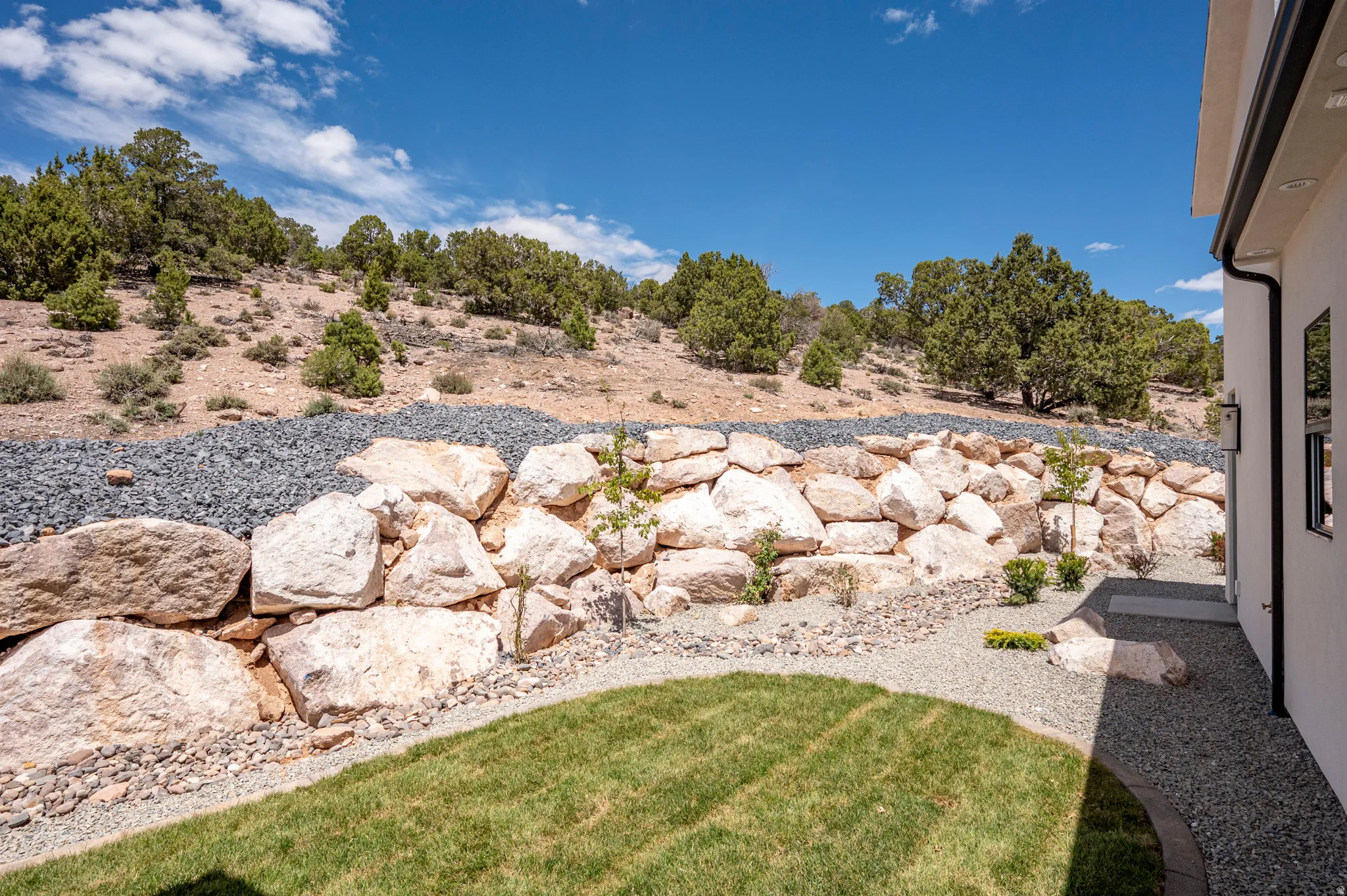 Terraced landscaping featuring a stacked stone retaining wall, gravel beds, and a manicured lawn