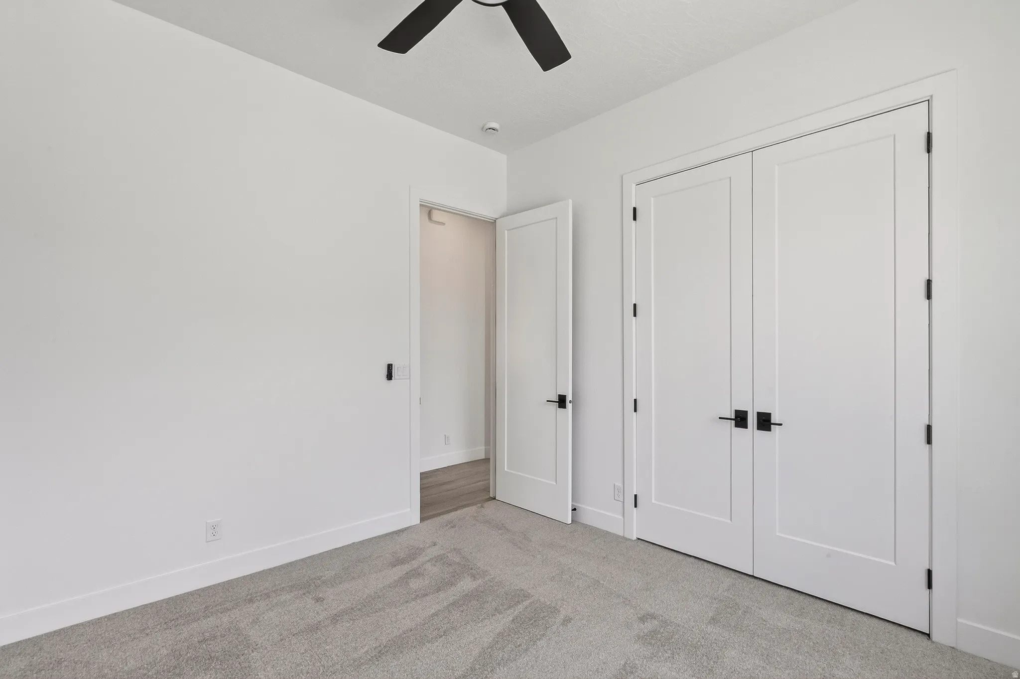 Interior space featuring white walls and grey patterned carpet