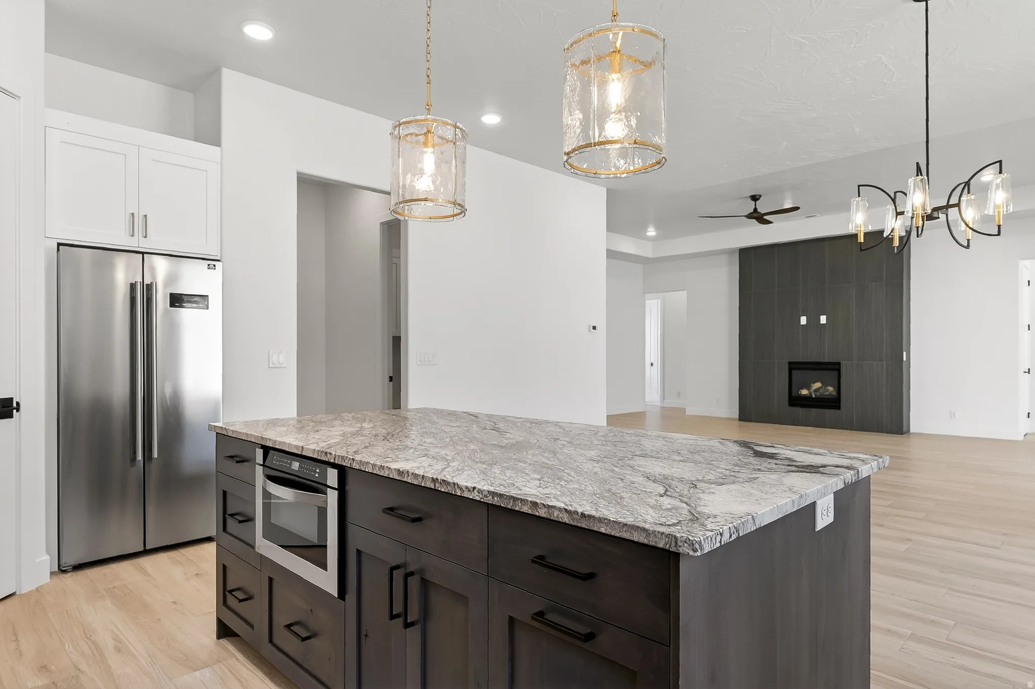 Kitchen island featuring a stone countertop, built-in microwave, and dark wood-finish cabinetry with black hardware