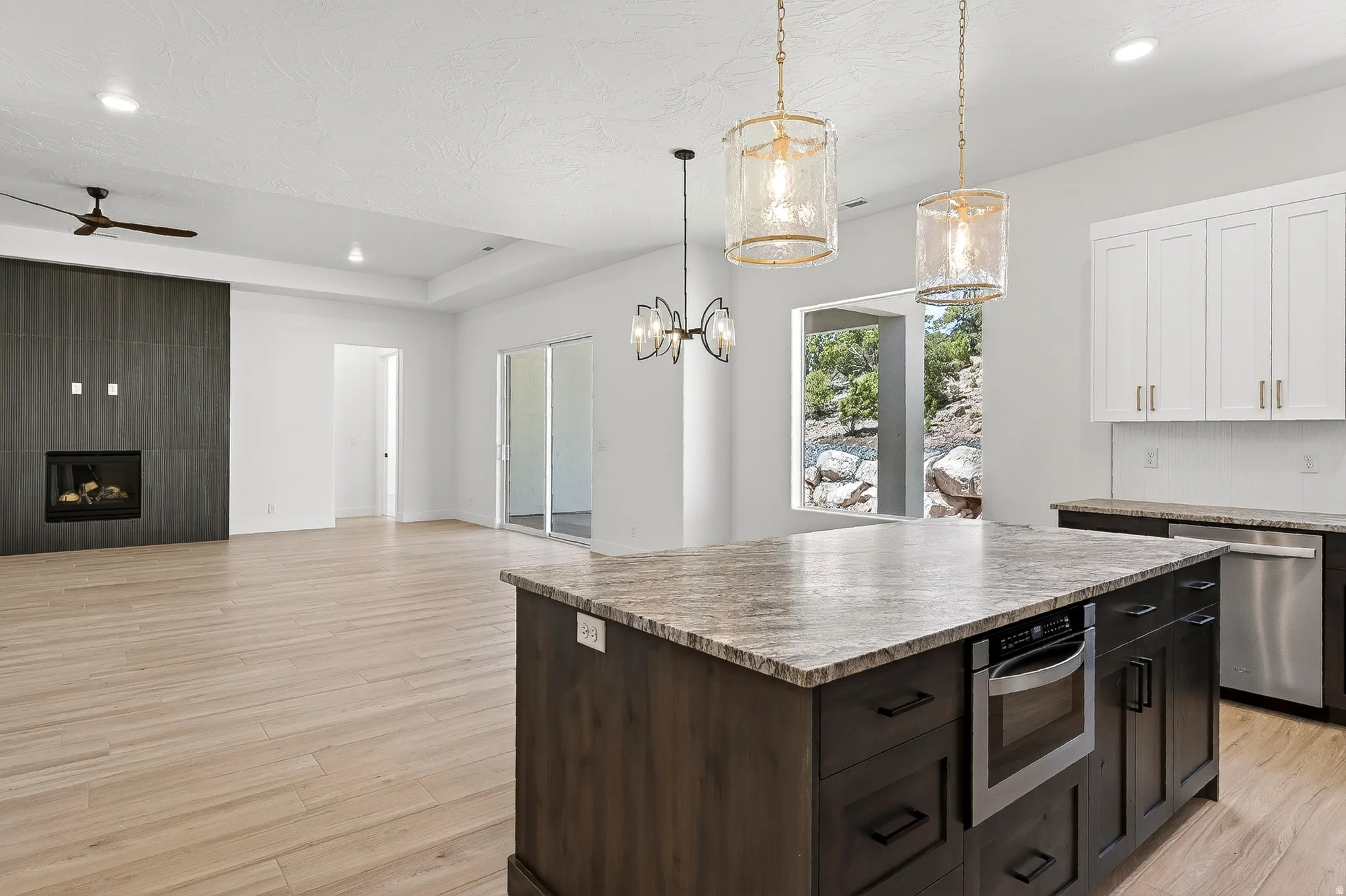 Open concept living space featuring wood-finish flooring, a contemporary fireplace with dark tile surround, and a kitchen island with stone countertop