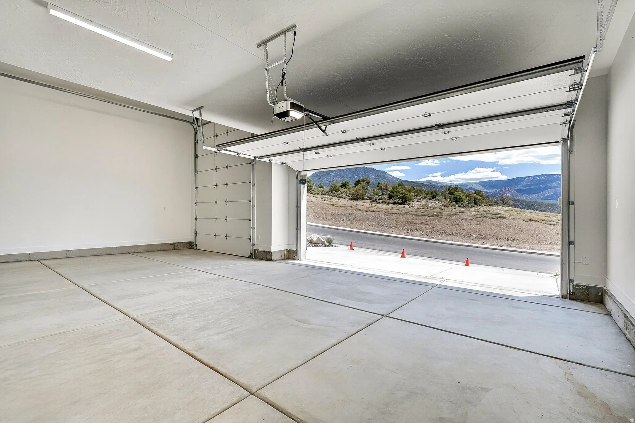 Spacious garage with concrete flooring, automatic garage door opener, and overhead strip lighting