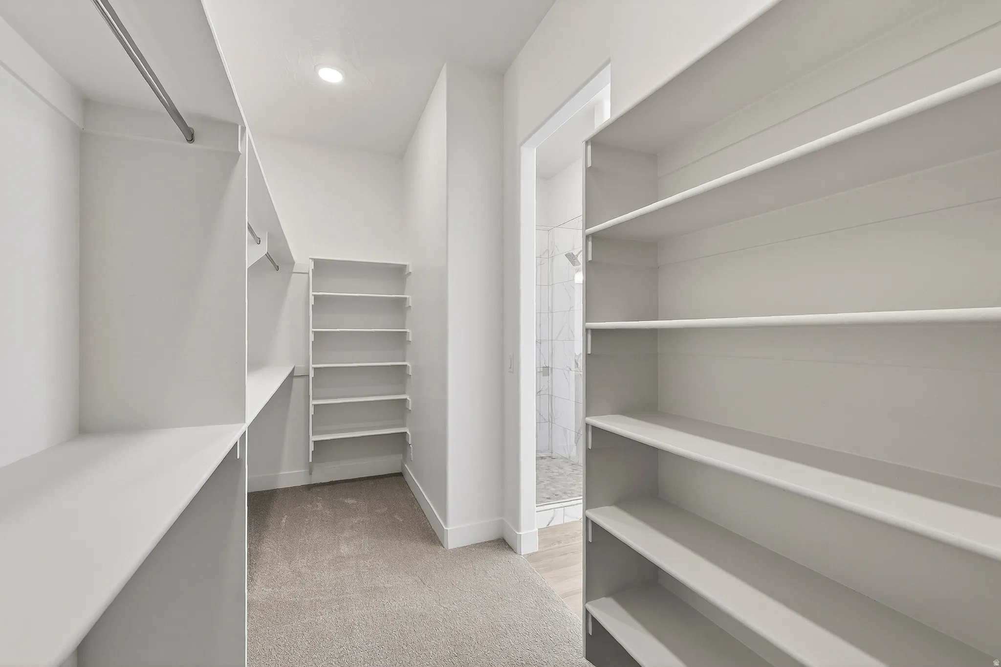 Walk-in closet with extensive built-in shelving, hanging rods, and recessed lighting