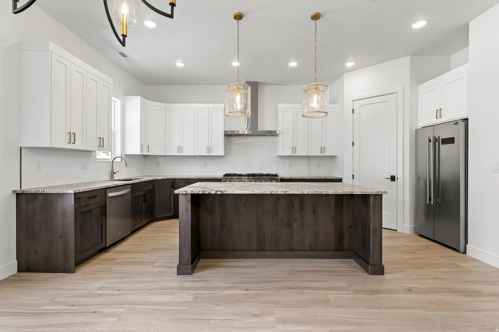 Modern kitchen featuring a two-toned cabinetry design, stainless steel appliances, and wood-finish flooring