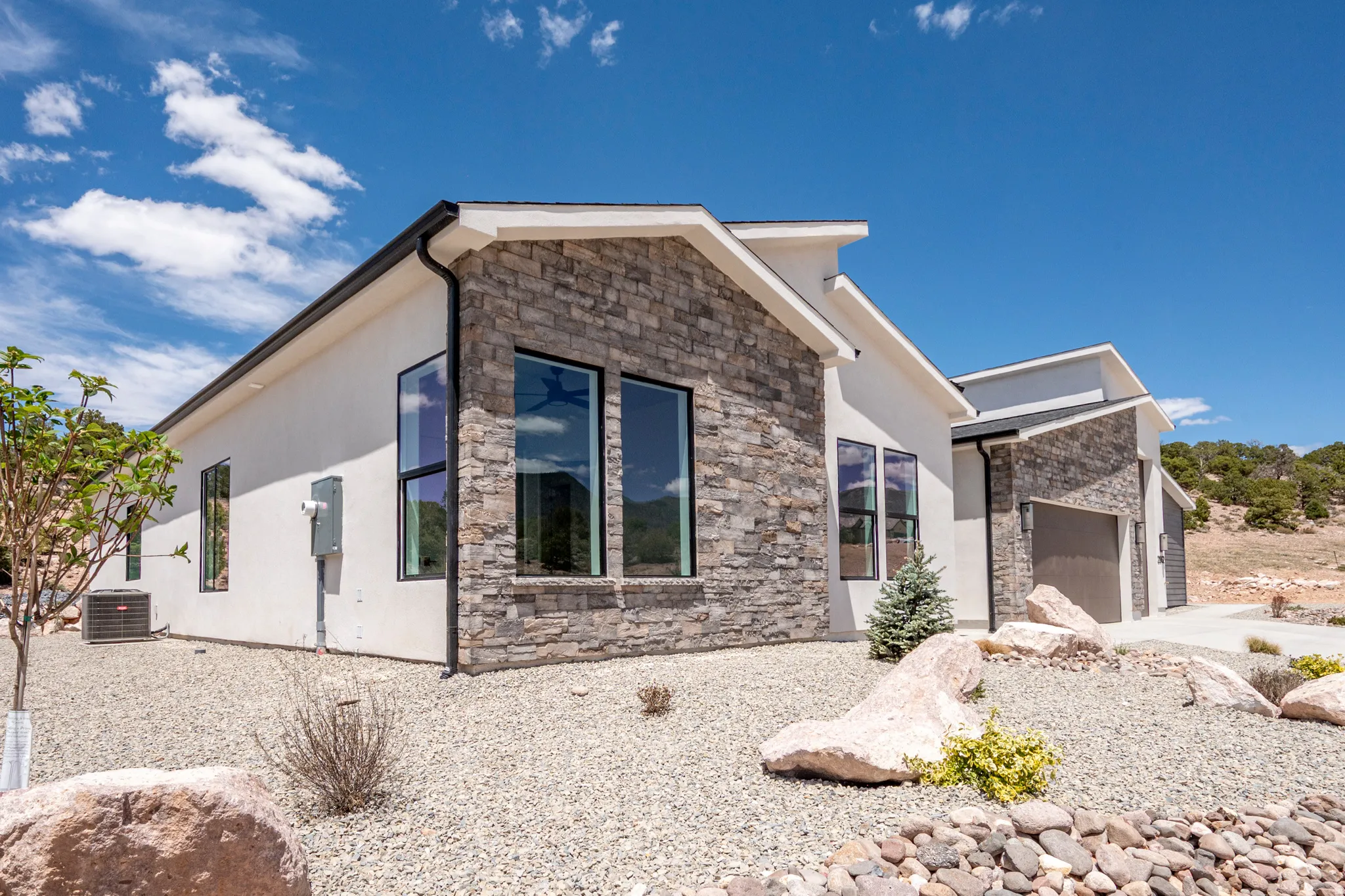 Contemporary exterior with stone veneer accents, stucco siding, and black-framed windows