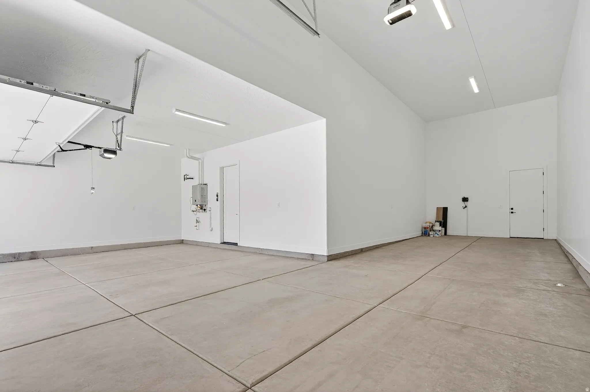 Spacious garage featuring a concrete floor, bright overhead lighting, and white painted walls