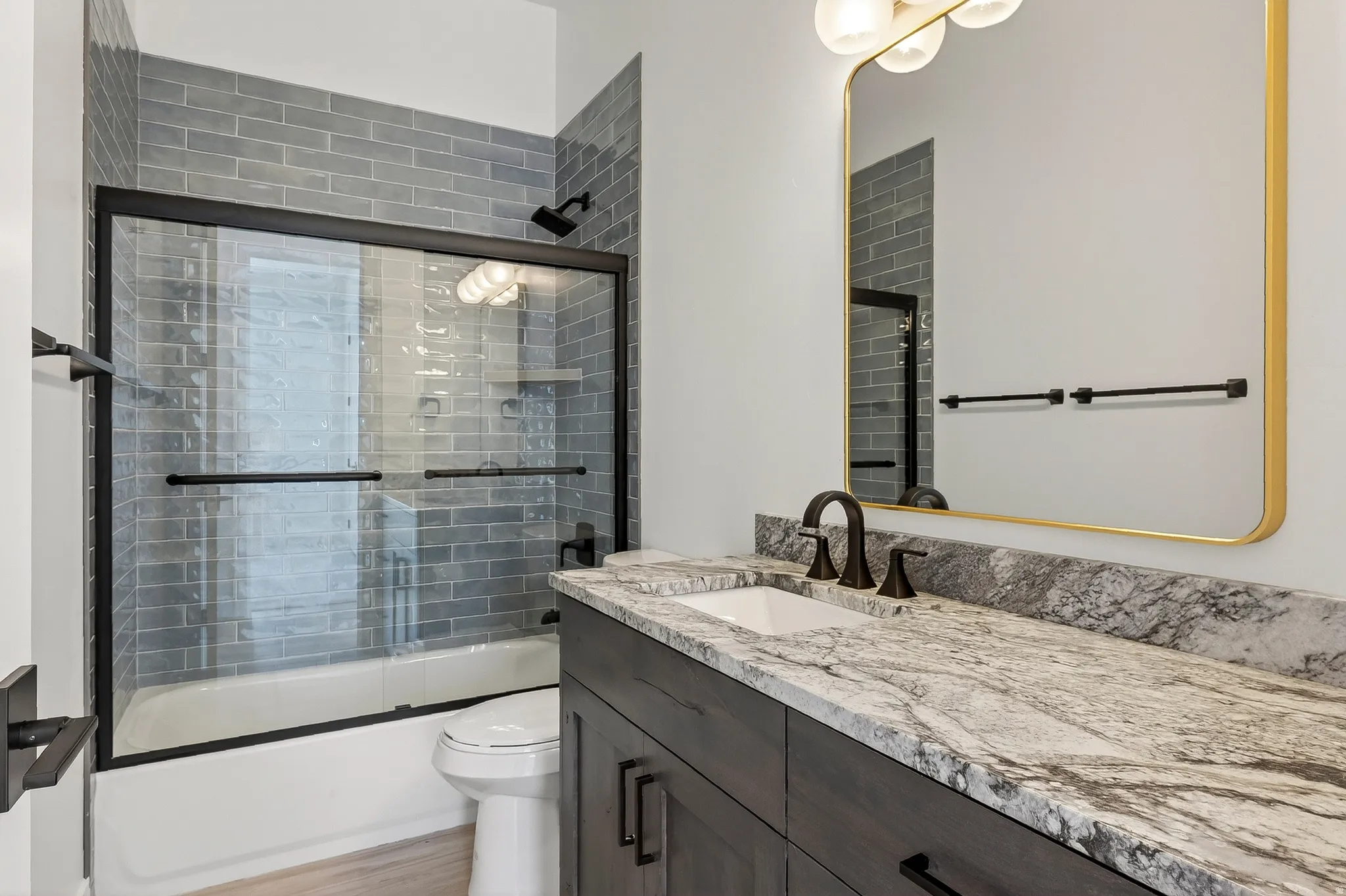 Bathroom featuring a vanity with a white rectangular sink and dark bronze faucet, set into a stone countertop