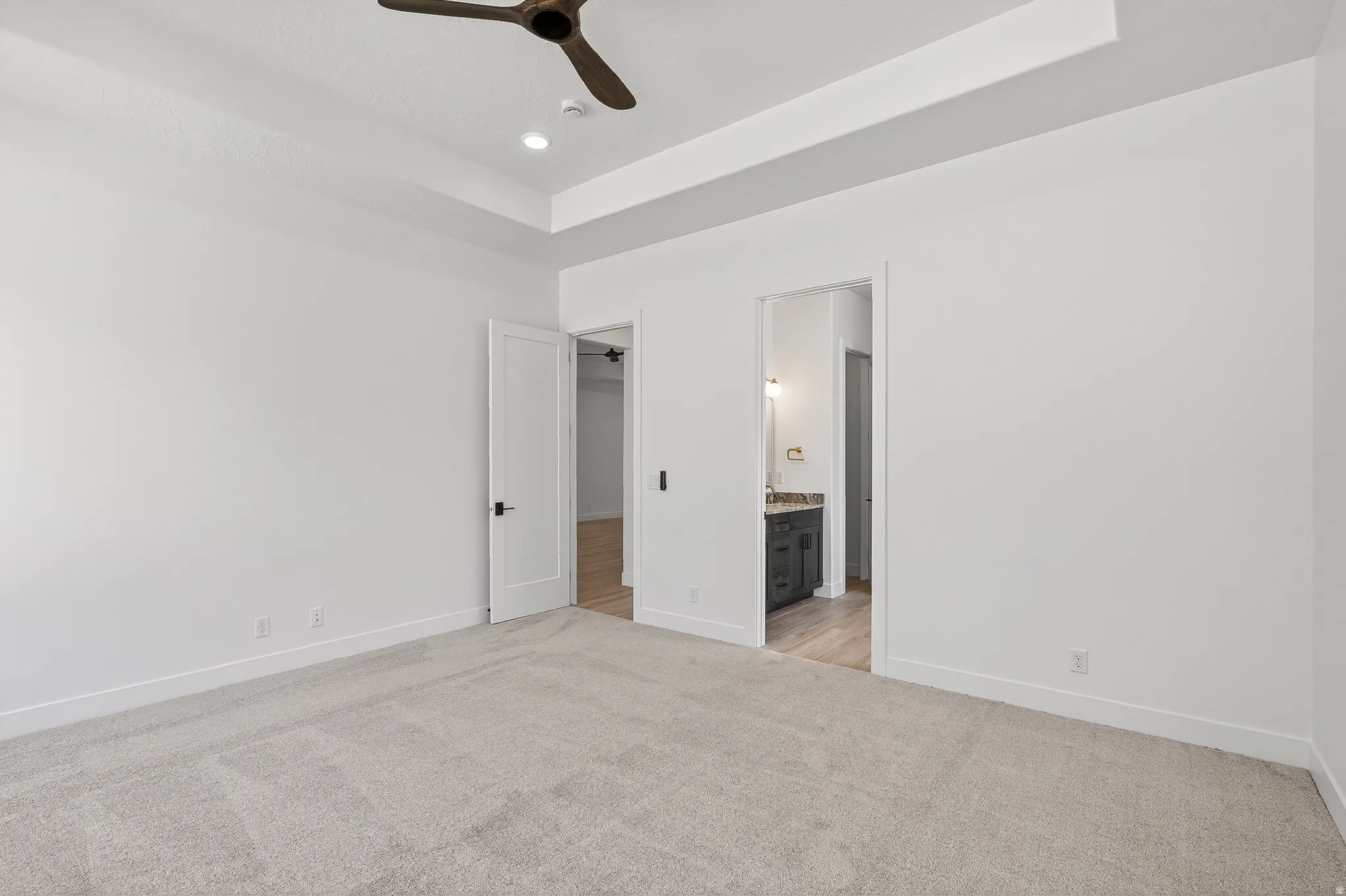 Carpeted room featuring a tray ceiling with a ceiling fan and recessed lighting