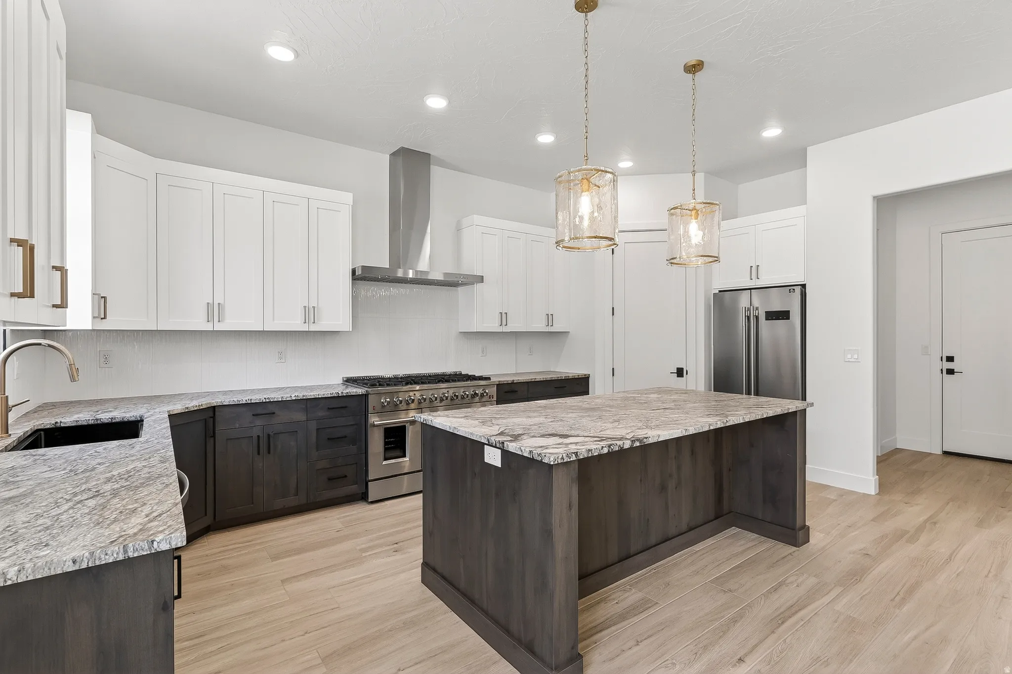 Modern kitchen featuring light wood-finish flooring, a central island with a stone countertop, and two-tone cabinetry