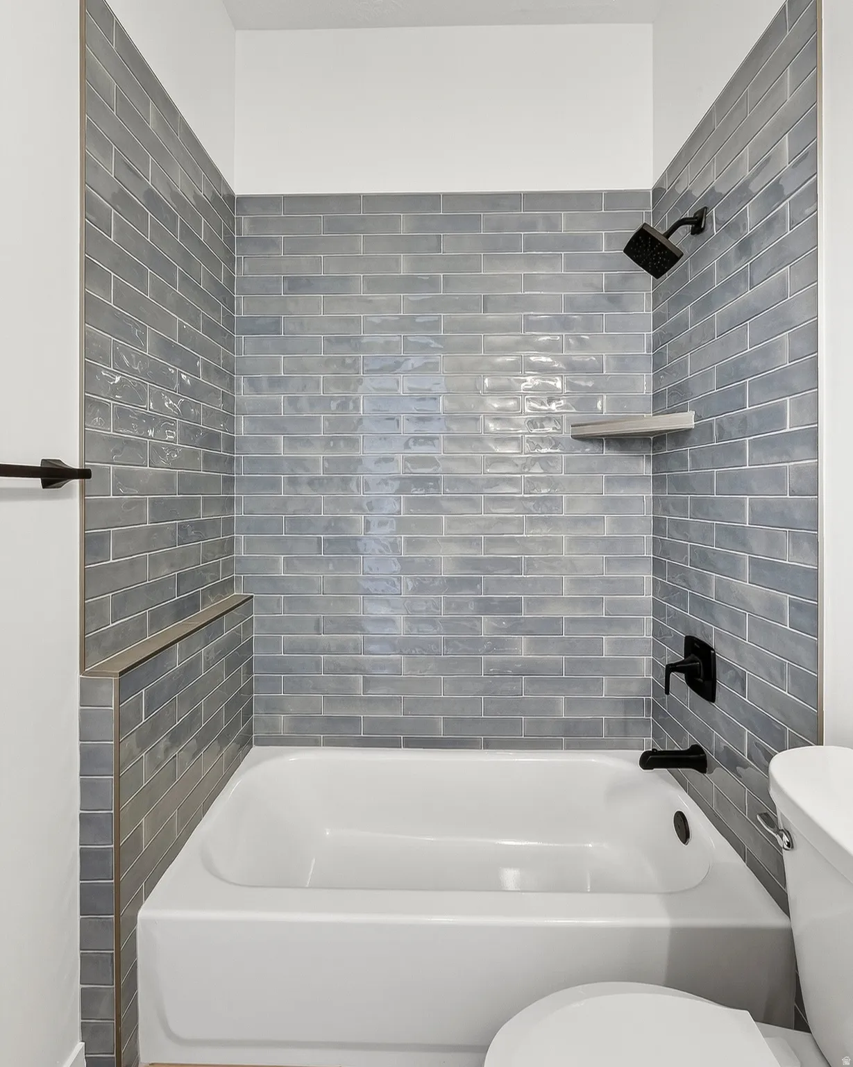 Bathroom featuring a white tub, matte black shower fixtures, and subway tile surround