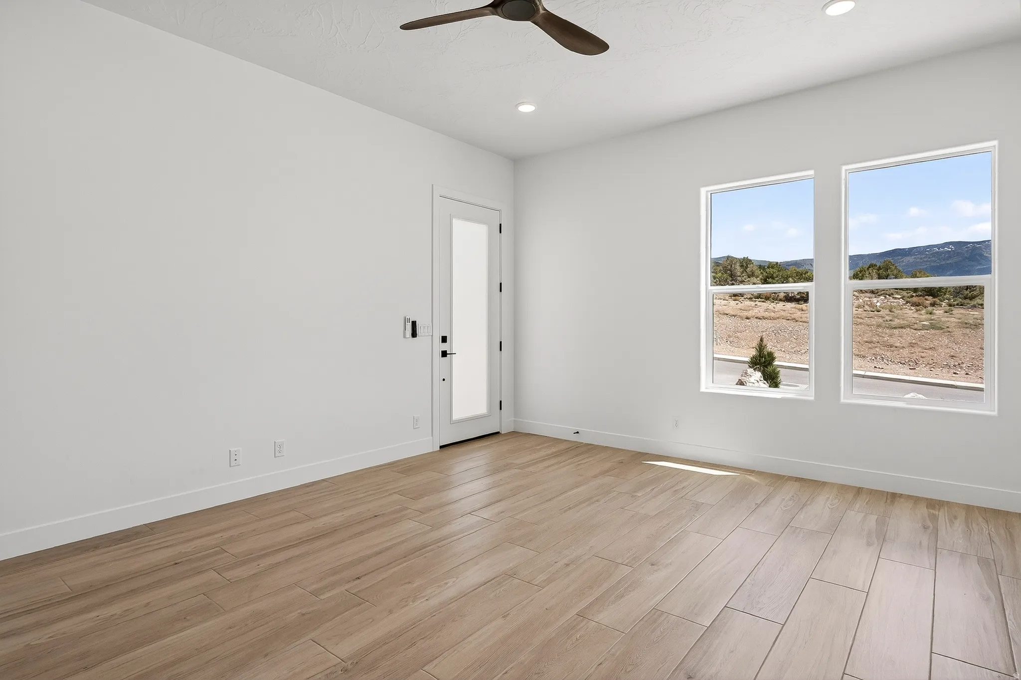 Bright room with wood-finish flooring and a contemporary ceiling fan