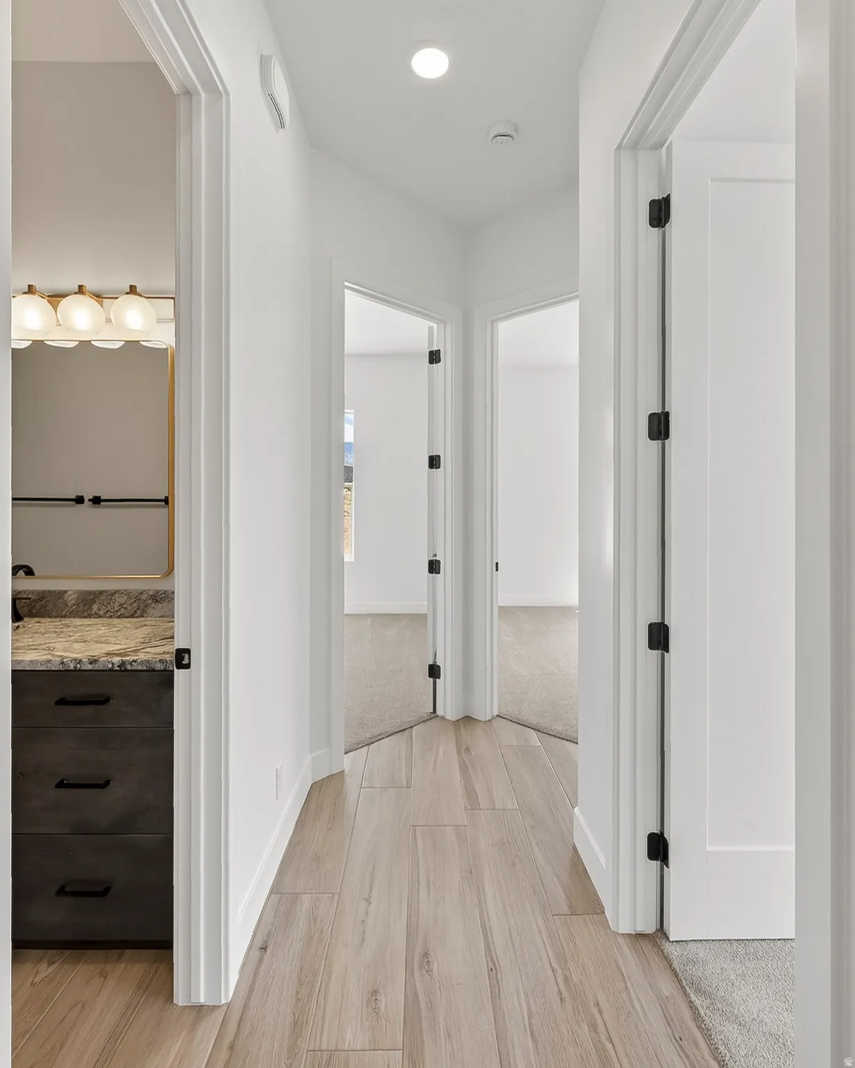 Hallway featuring wood-finish flooring, white walls, and recessed lighting