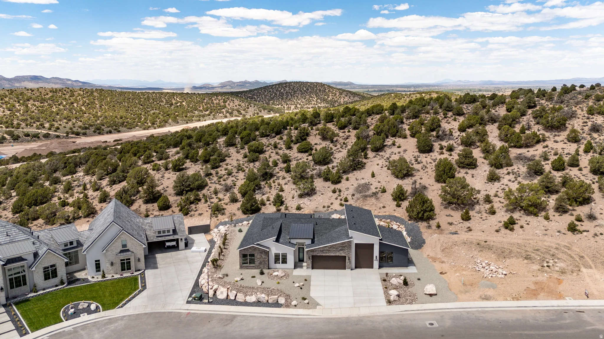 Modern residential architecture featuring a dark gray roof, light-colored stone accents, and an attached two-car garage