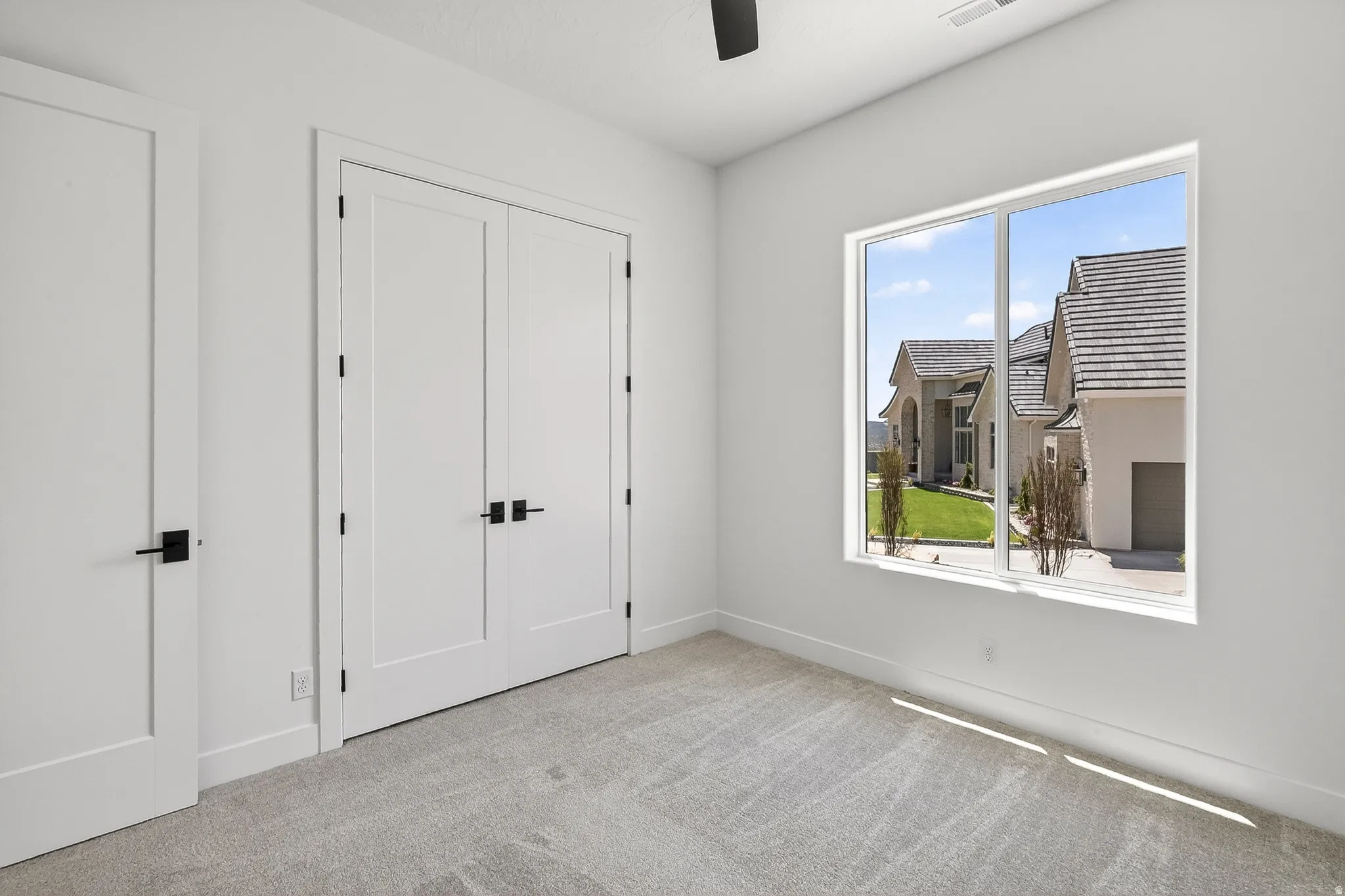Bright interior space featuring a large window, carpeted flooring, and white walls