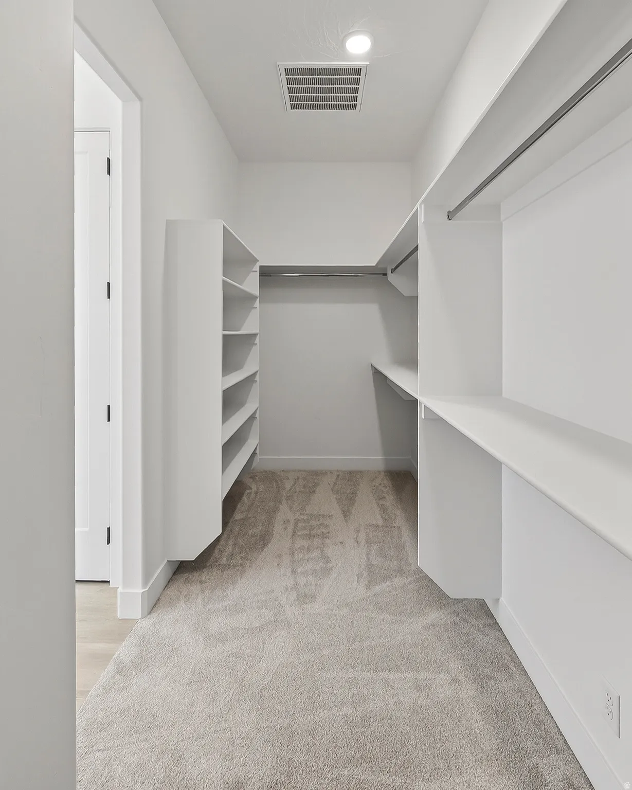 Walk-in closet featuring built-in shelving, hanging rods, recessed lighting, and light-toned carpet flooring