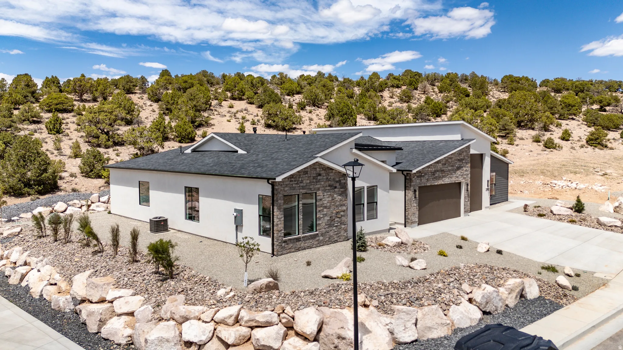 Modern ranch-style home featuring a dark shingle roof and a two-car garage