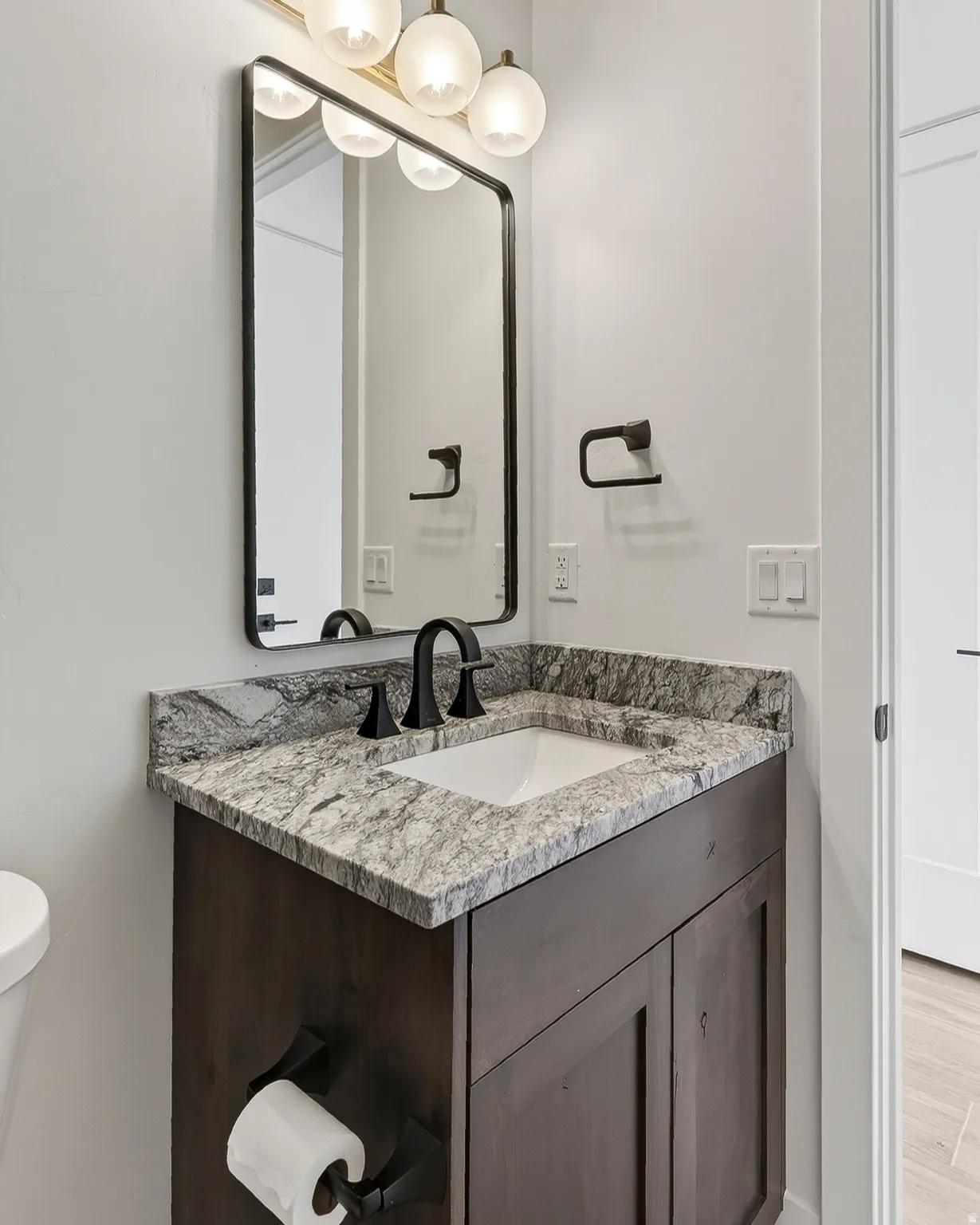 Powder room featuring a dark wood-finish vanity with a light-toned granite countertop and an undermount sink