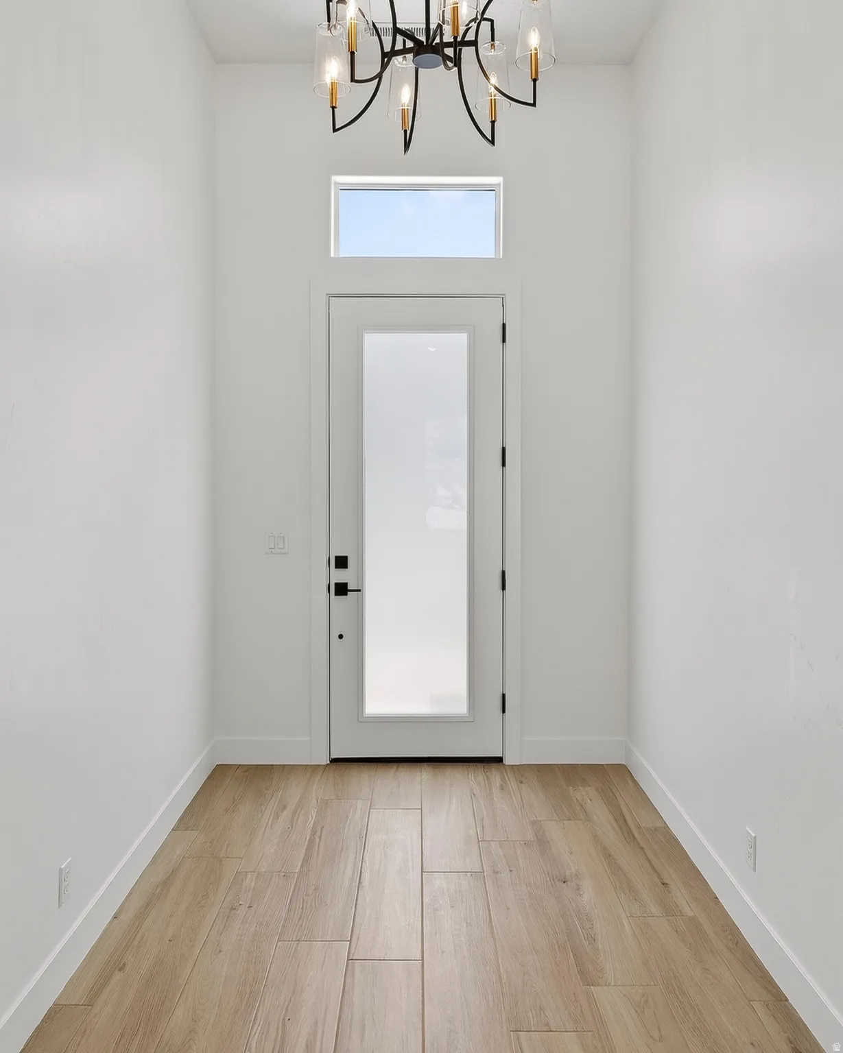 Entryway featuring a contemporary chandelier, transom window, and wood-finish tile flooring