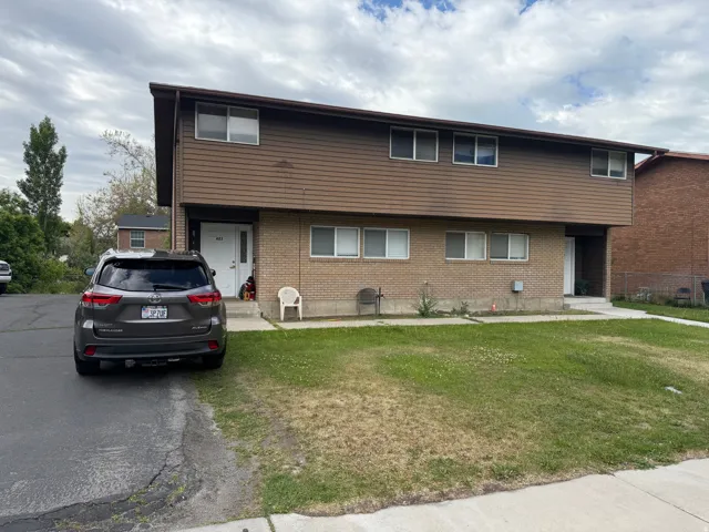 Two-story property featuring brick and siding exterior, multiple windows, front entry, paved driveway, and a grass lawn