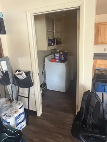 Dedicated utility area featuring wood-finish flooring, overhead cabinetry, and appliance hookups