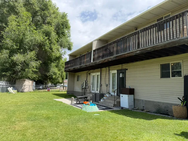 Spacious backyard featuring a large tree and a ground-level concrete patio