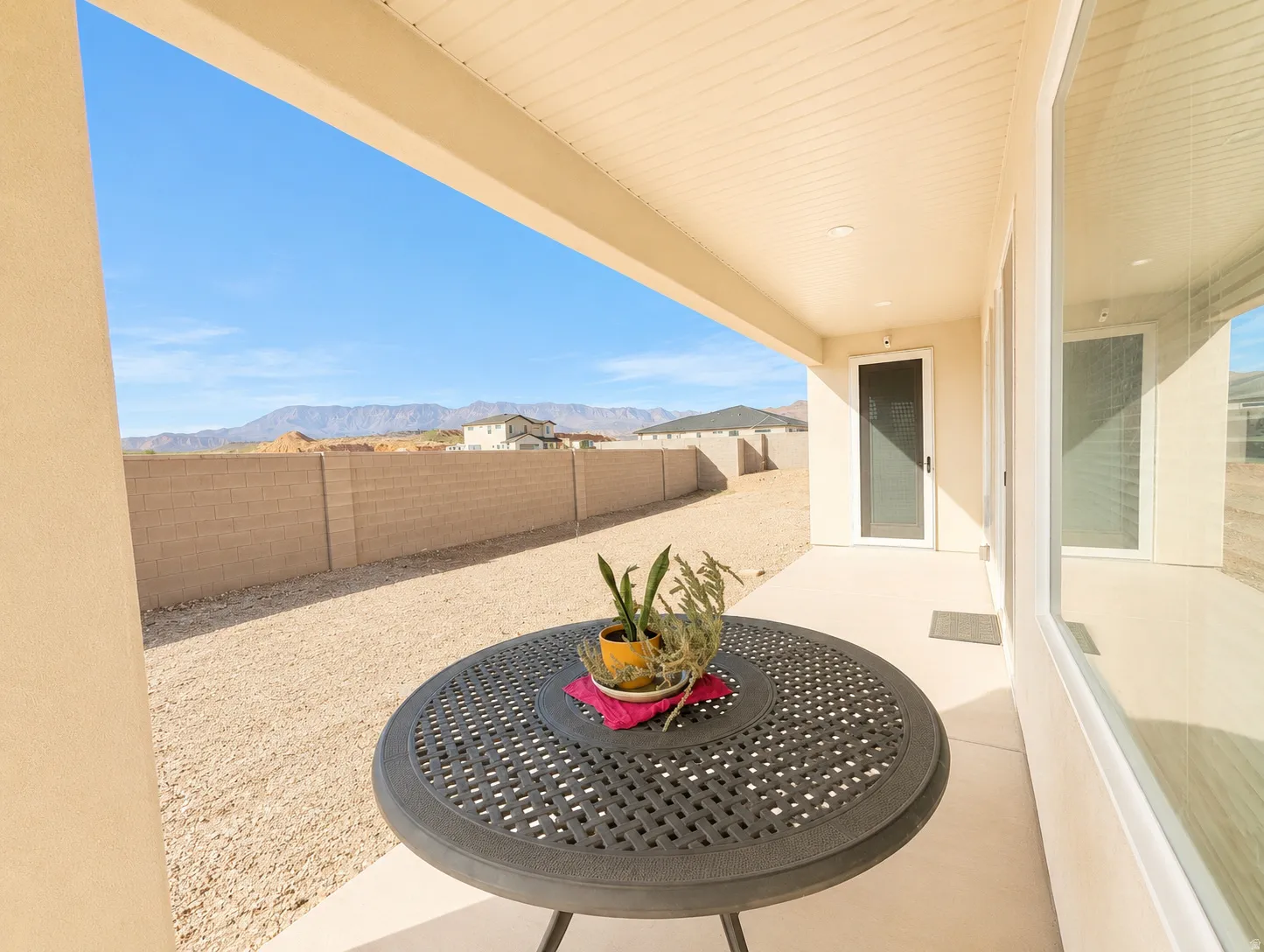 Covered patio area with concrete flooring, stucco exterior, and a distant mountain backdrop