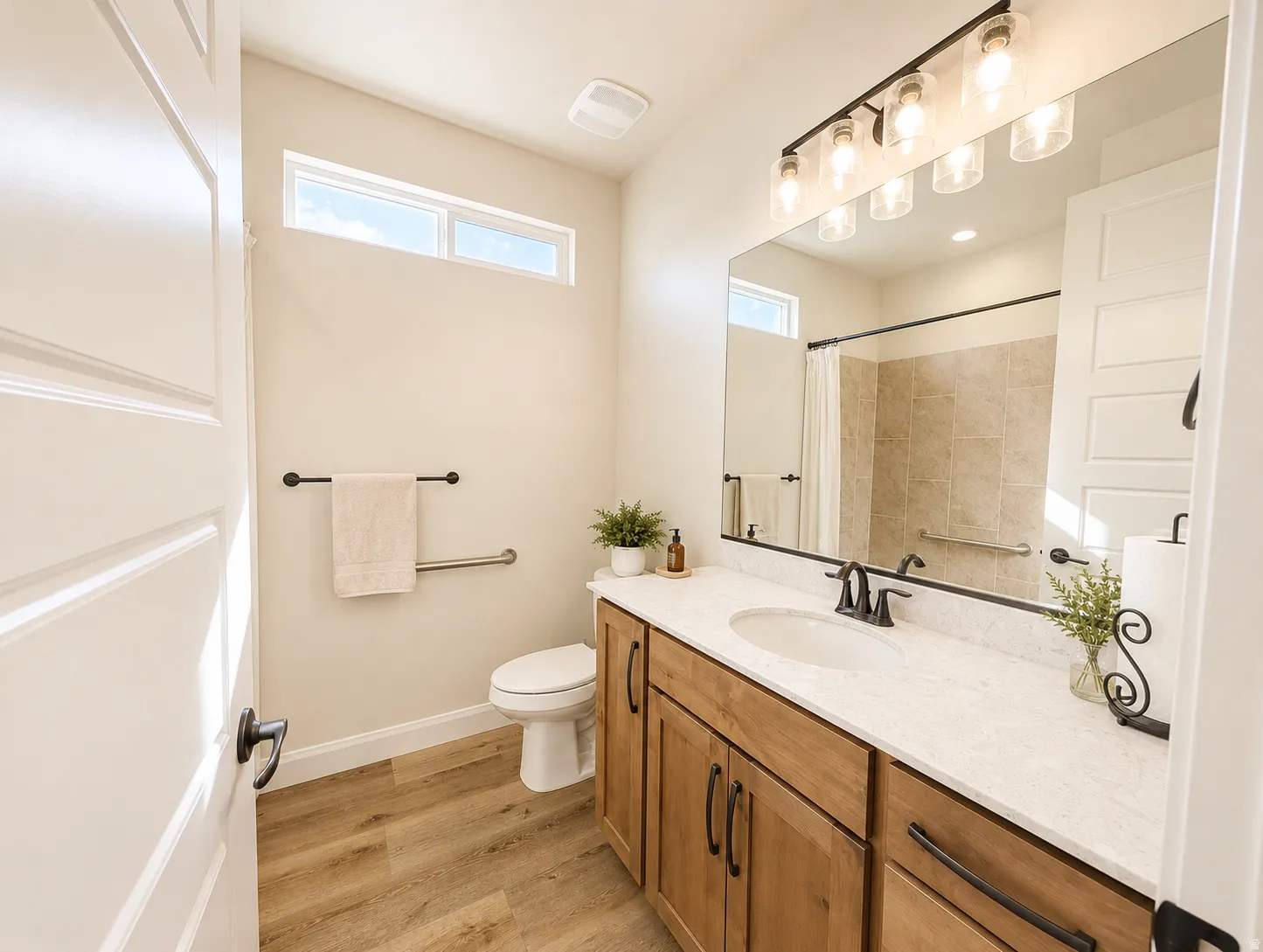Bathroom featuring a wood-finish vanity with a light-toned countertop, a large framed mirror, and a multi-bulb light fixture